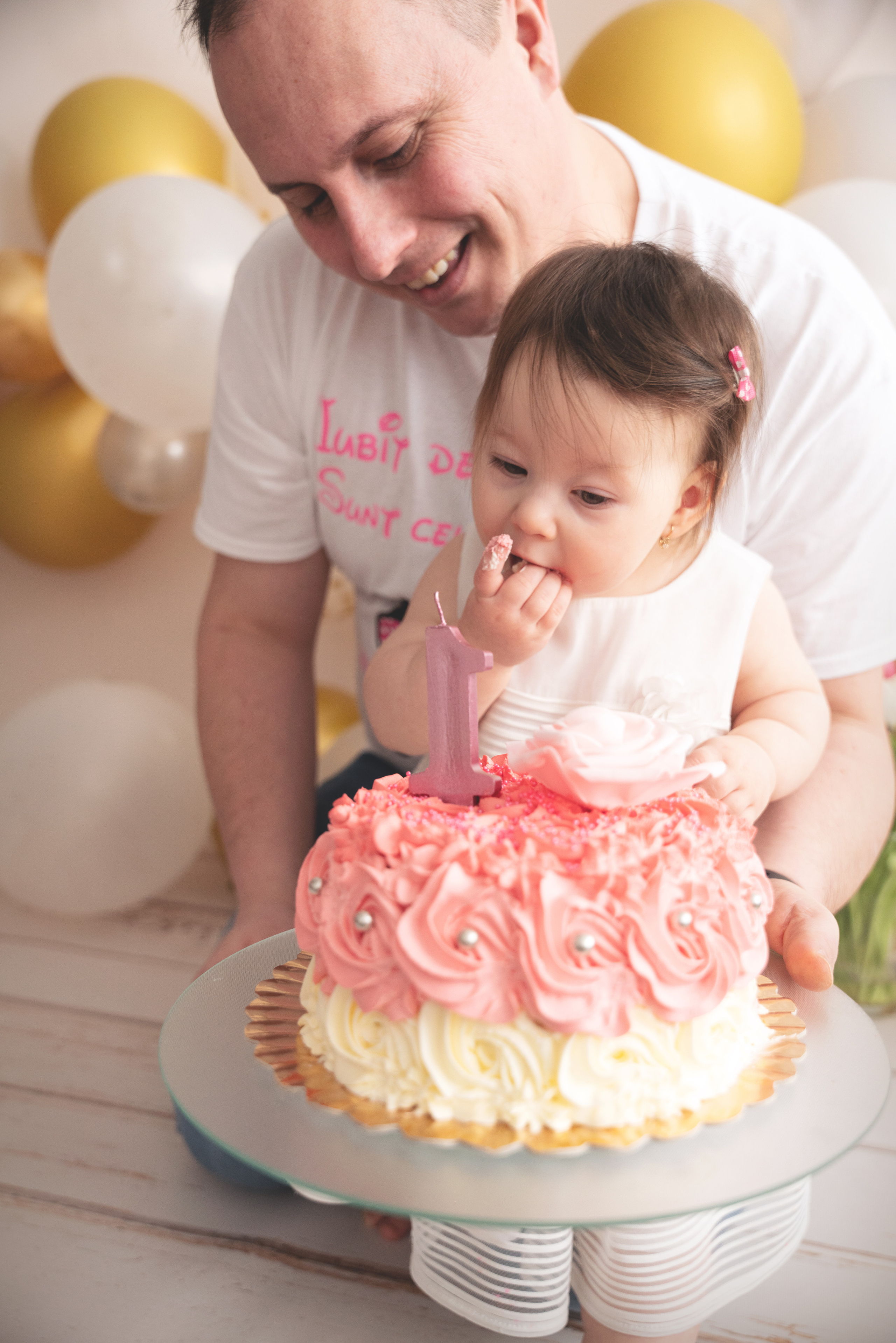vater und einjährige tochter essen kuchen mit ihren händen und lachen