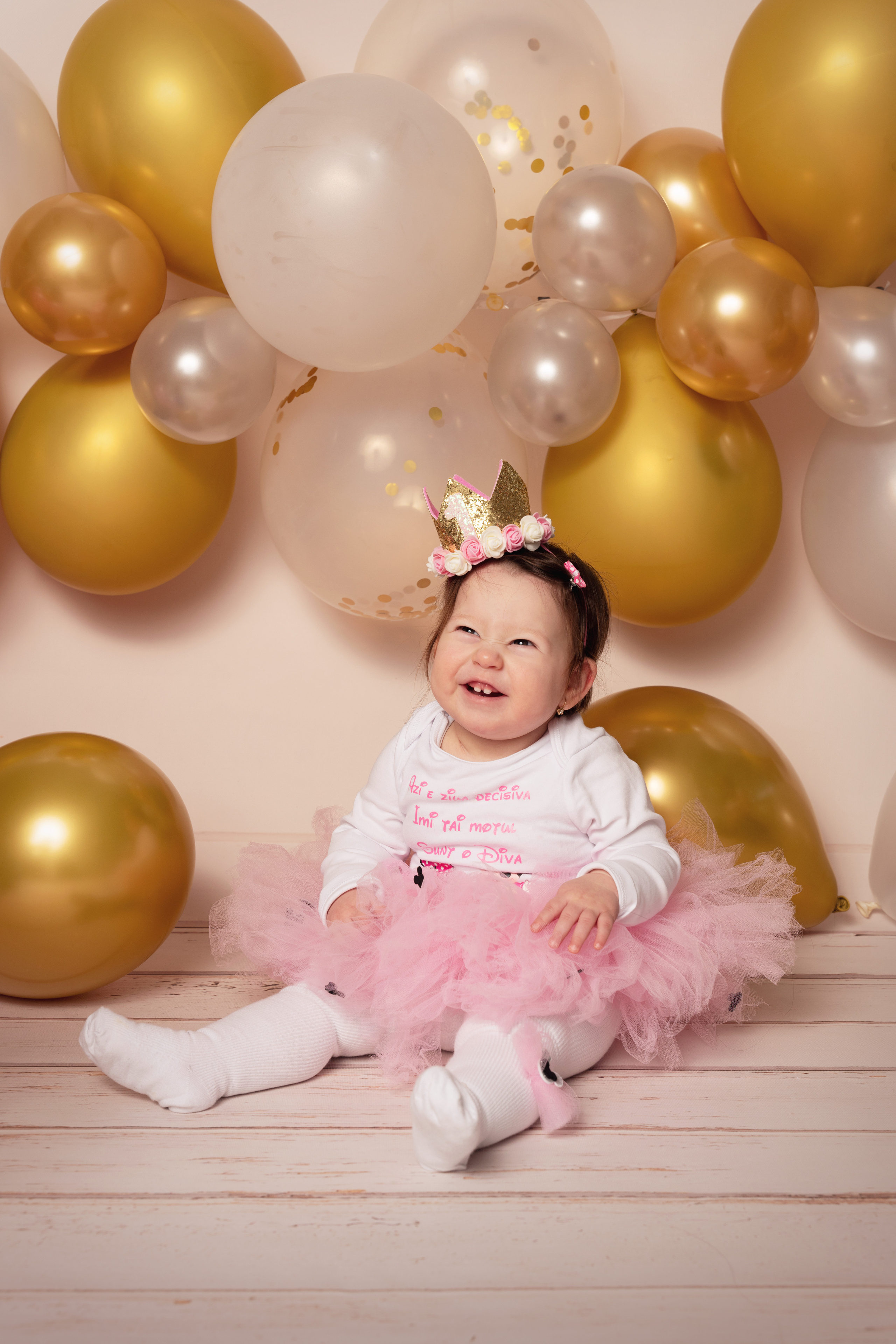 Ein Mädchen, das auf dem Boden sitzt und von Luftballons auf dem Kopf umgeben ist, hat eine Krone