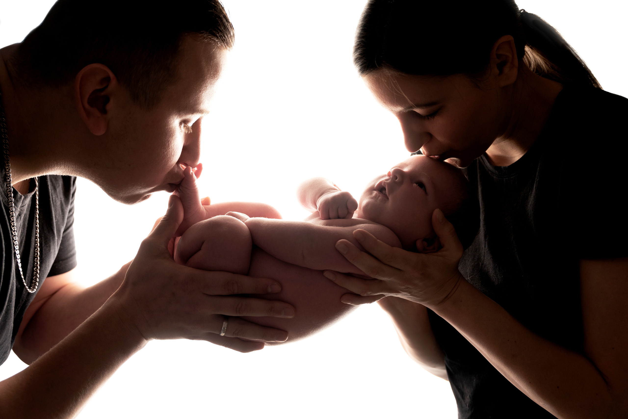 papa küsst das Baby auf die Fersen und Mama küsst das Baby auf die Stirn