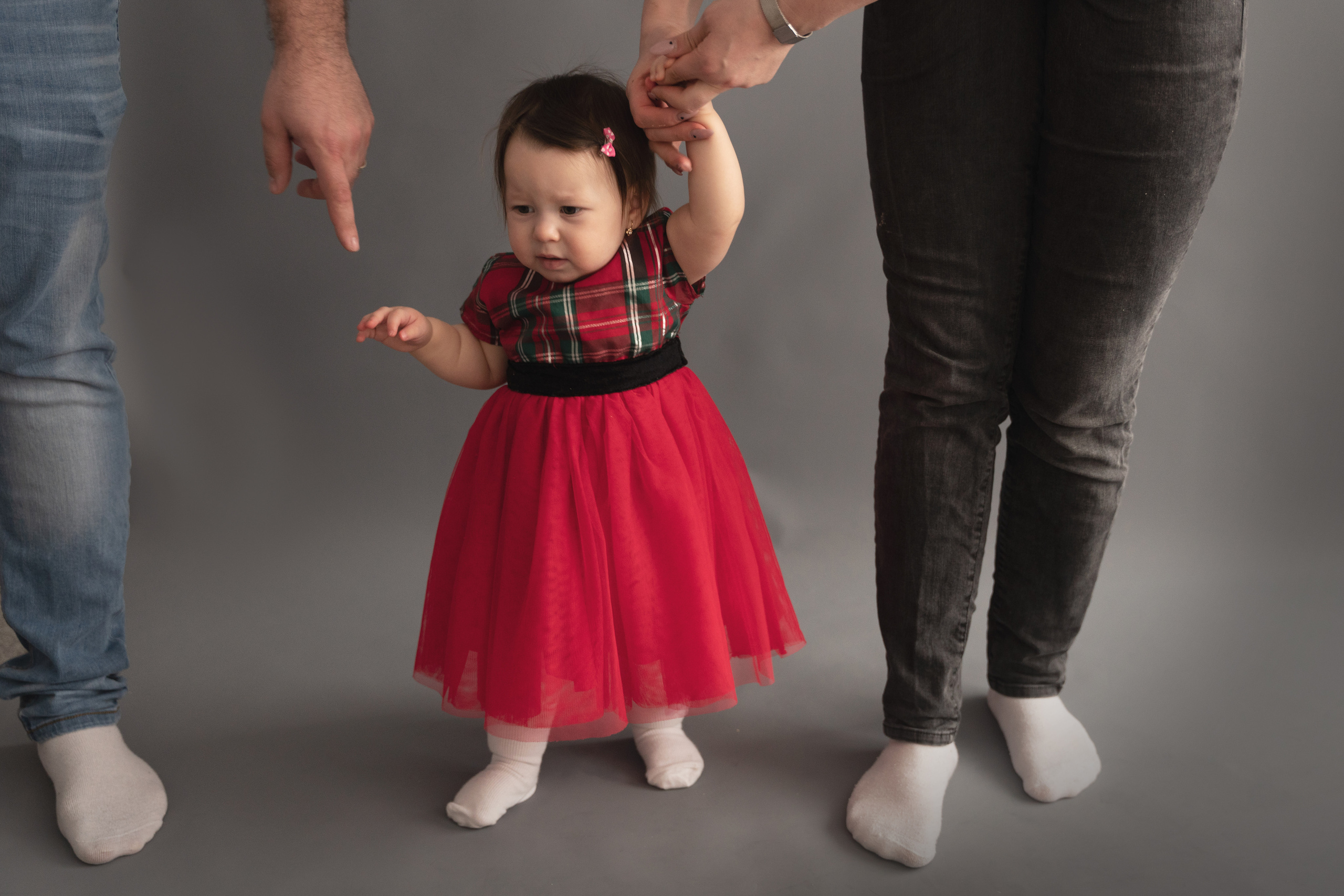 das kind hält die hände von mama und papa und macht die ersten schritte