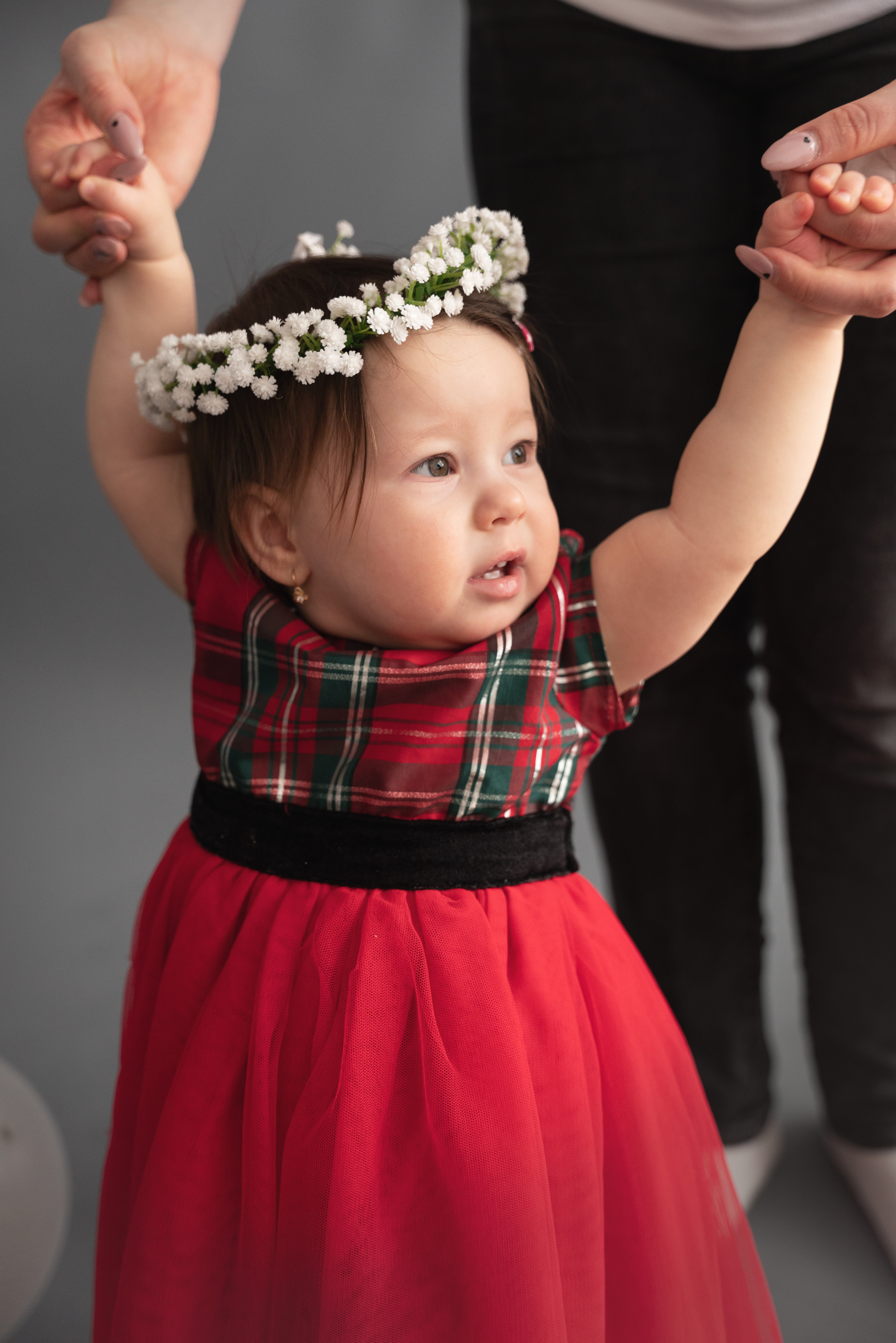 das kind hält die hände von mama und papa und macht die ersten schritte