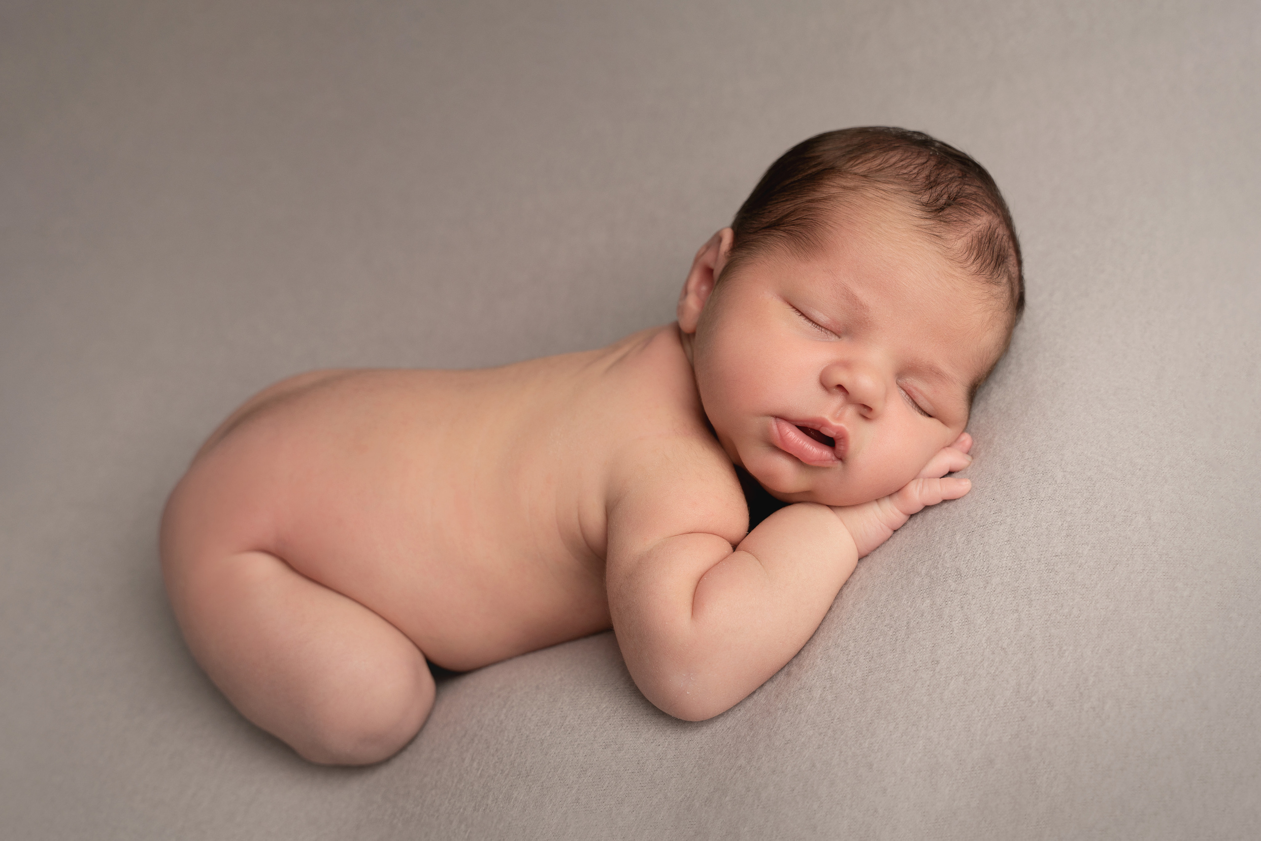 Grundhaltung eines Neugeborenen auf einem Sitzsack auf beigem Hintergrund