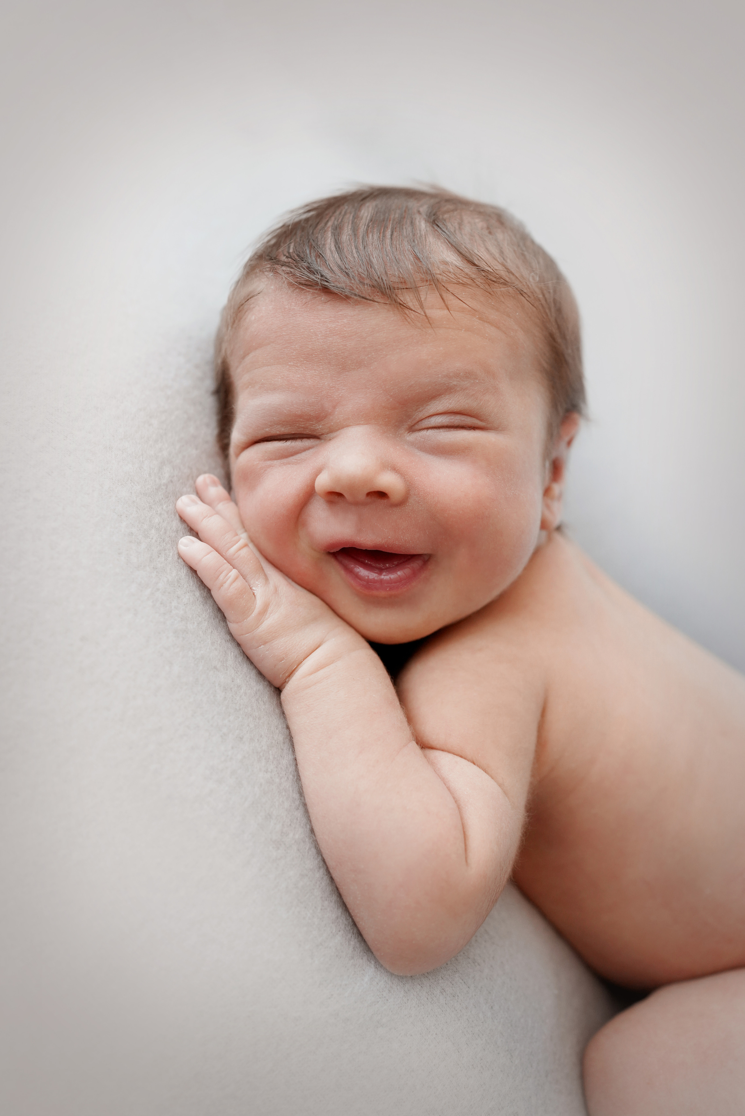 Ein zwei Wochen alter Junge lacht bei einem Neugeborenen-Fotoshooting in die Kamera