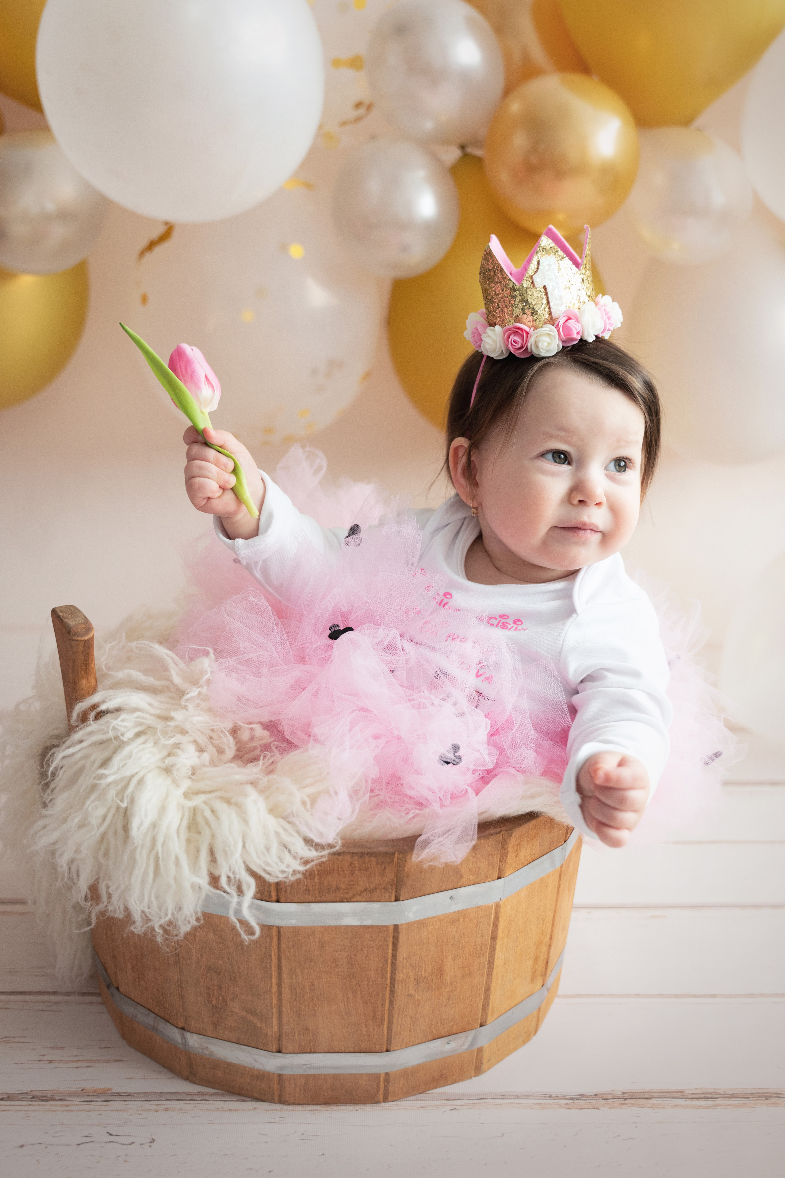 kleine Prinzessin sitzt in einem Holzbecken und lächelt