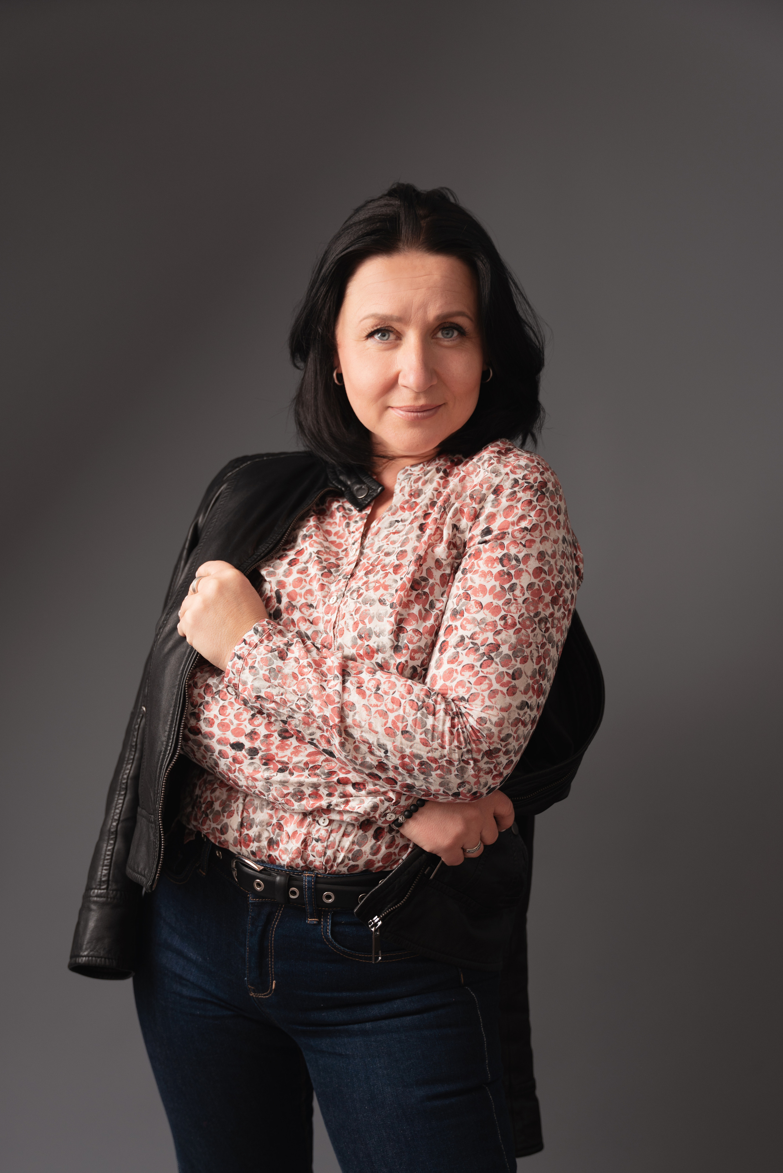 Mädchen mit einer Jacke auf der Schulter schaut in die Kamera