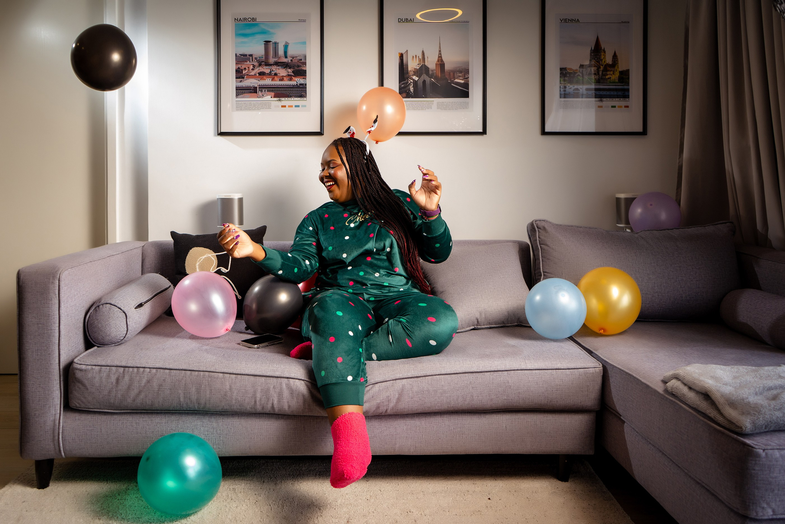 Bubbly photo of a lady in her Christmas pajamas with balloons on the couch- creative Christmas photoshoot