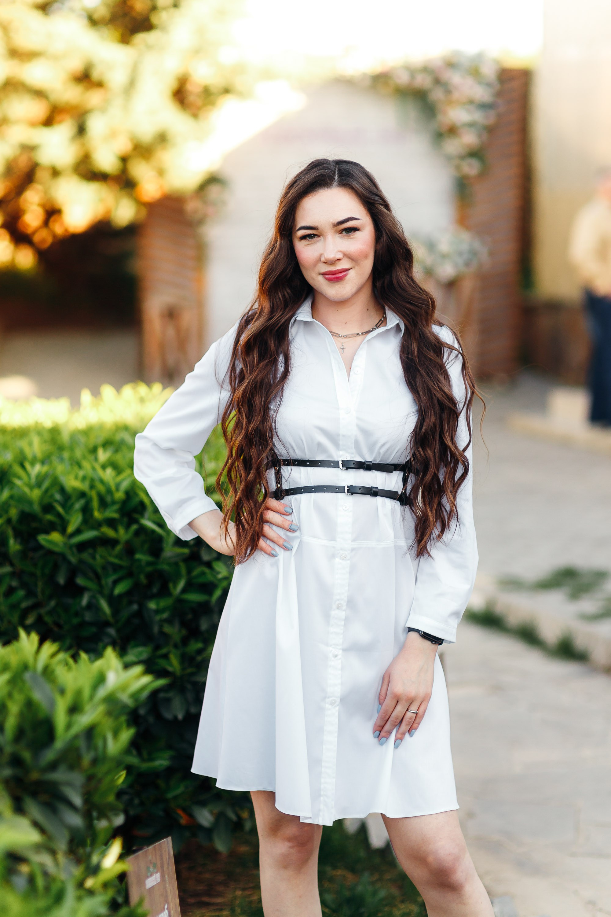 Young woman in white dress near greenery