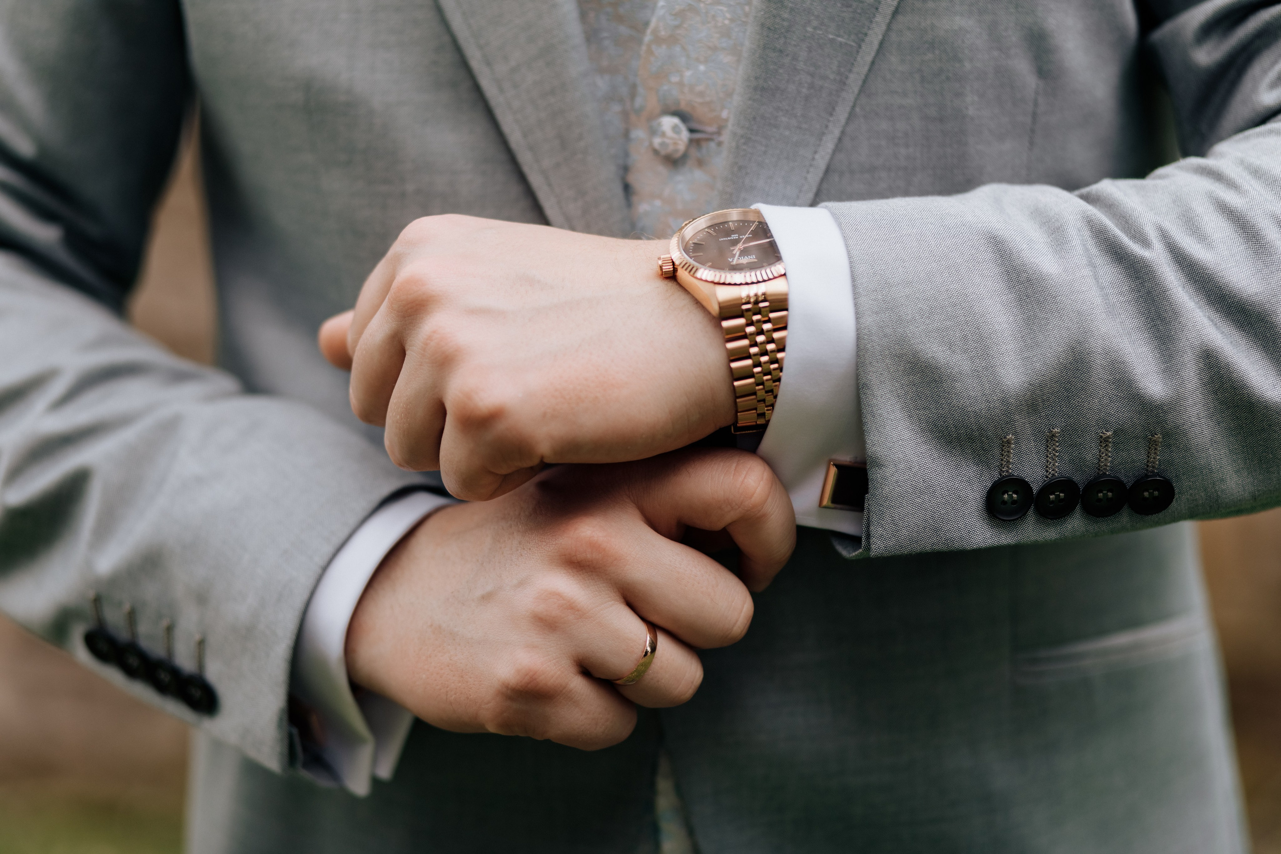 Die Hände des Bräutigams, wie er die Ärmel seines Hemdes richtet, während seine Uhr sichtbar ist. 
