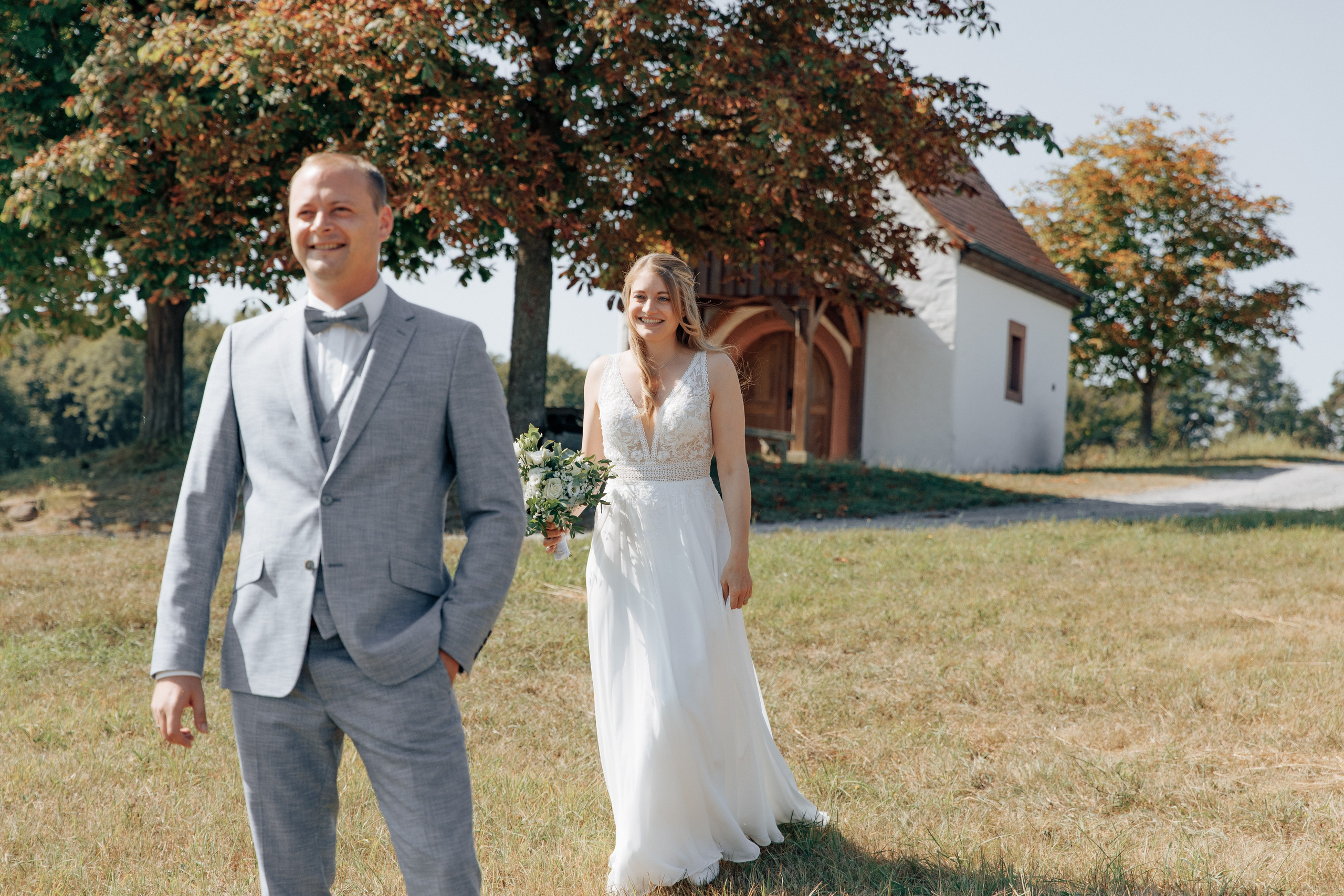 Braut geht während des “First Look” zum Bräutigam vor der Kapelle in Hausen.