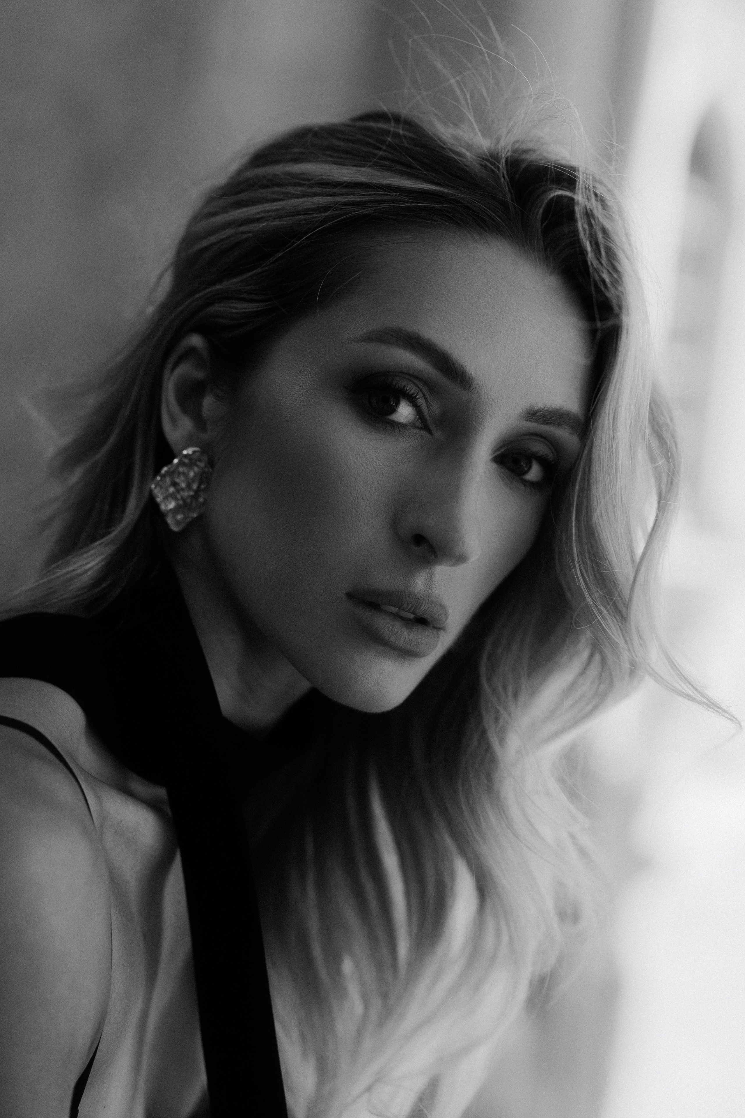 Intimate black and white close-up portrait of an elegant blonde woman looking into the camera in Dresden, Germany. Timeless female and editorial portrait photography by a photographer based near Leipzig and Wurzen. Интимный чёрно-белый крупный портрет элегантной блондинки, смотрящей в камеру, в Дрездене, Германия. Вневременная женская и редакционная портретная фотография от фотографа из региона Лейпцига и Вурцена.
