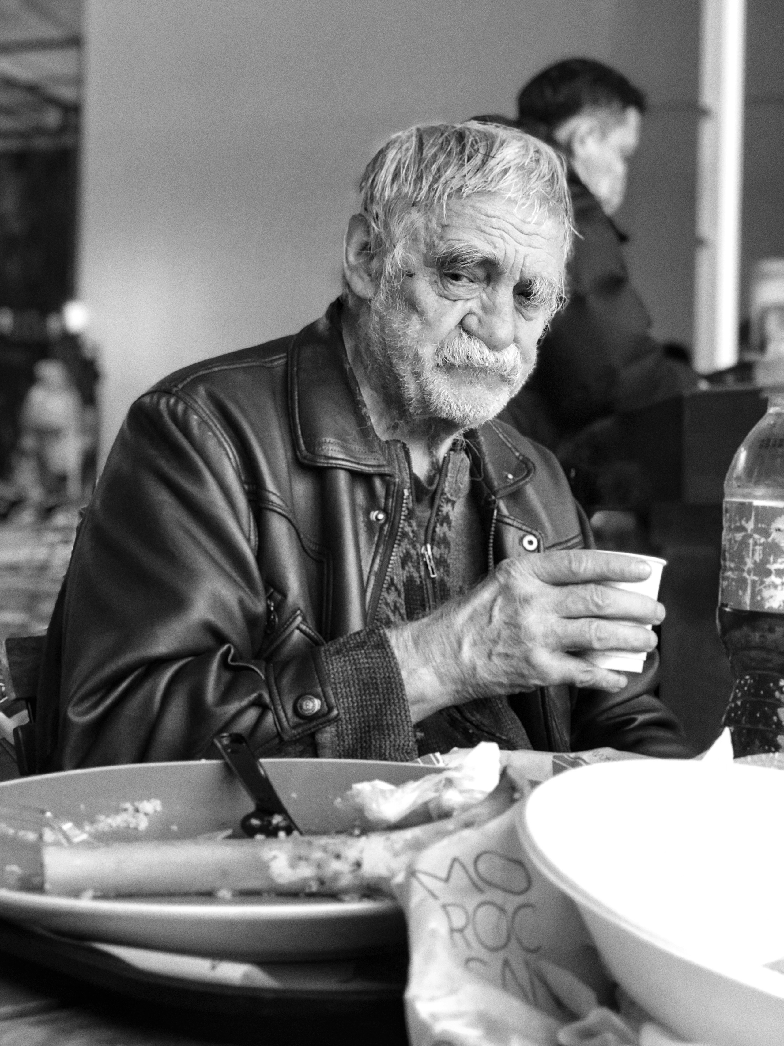 Magnum photo agency. Awards photo. Portrait of a poor and hungry old man looking at the remains of someone else's dinner.