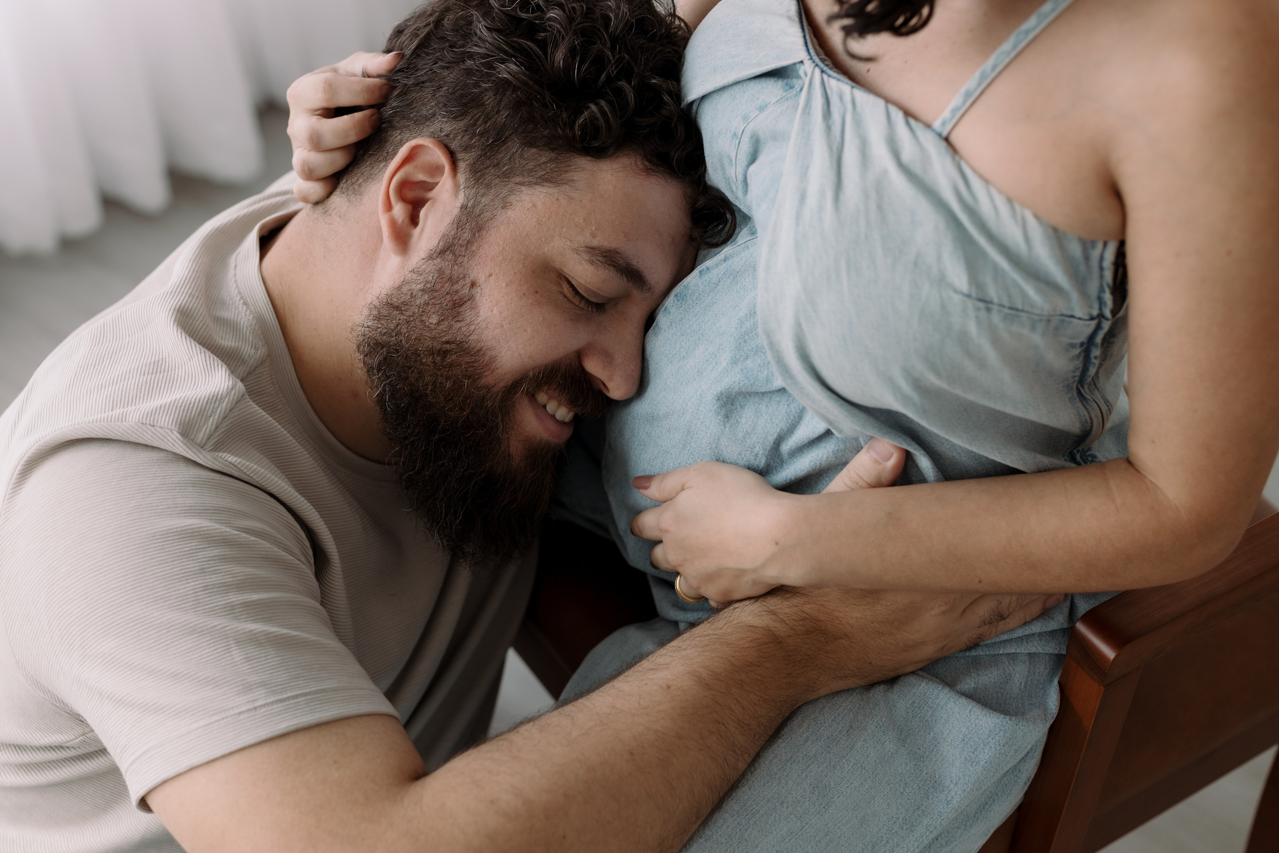 Foto ensaio gestante com pai abraçando a barriga com afeto