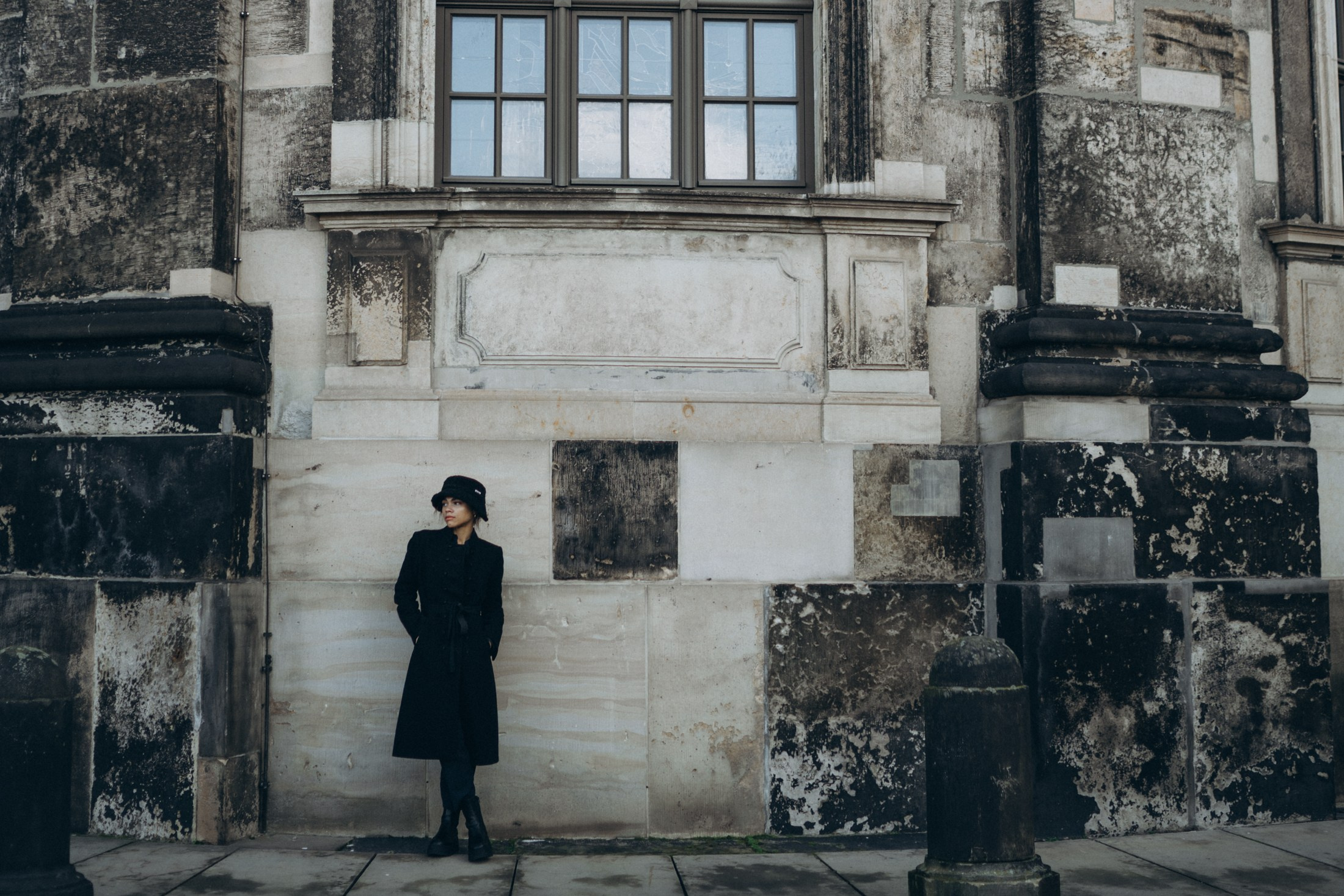 Frau in schwarzem Mantel vor historischer Fassade in Dresden – künstlerische Portraitfotografie