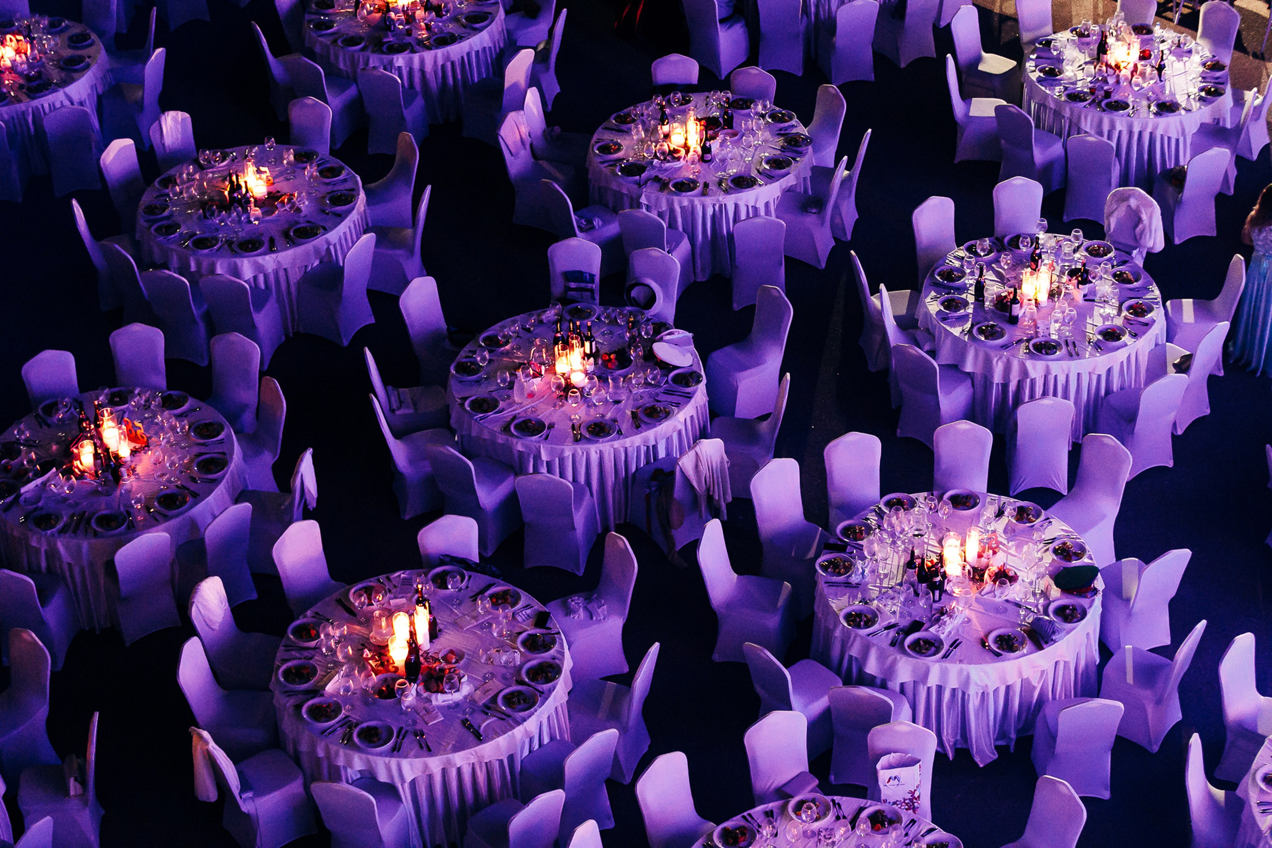 Elegant dinner tables at event with purple lighting