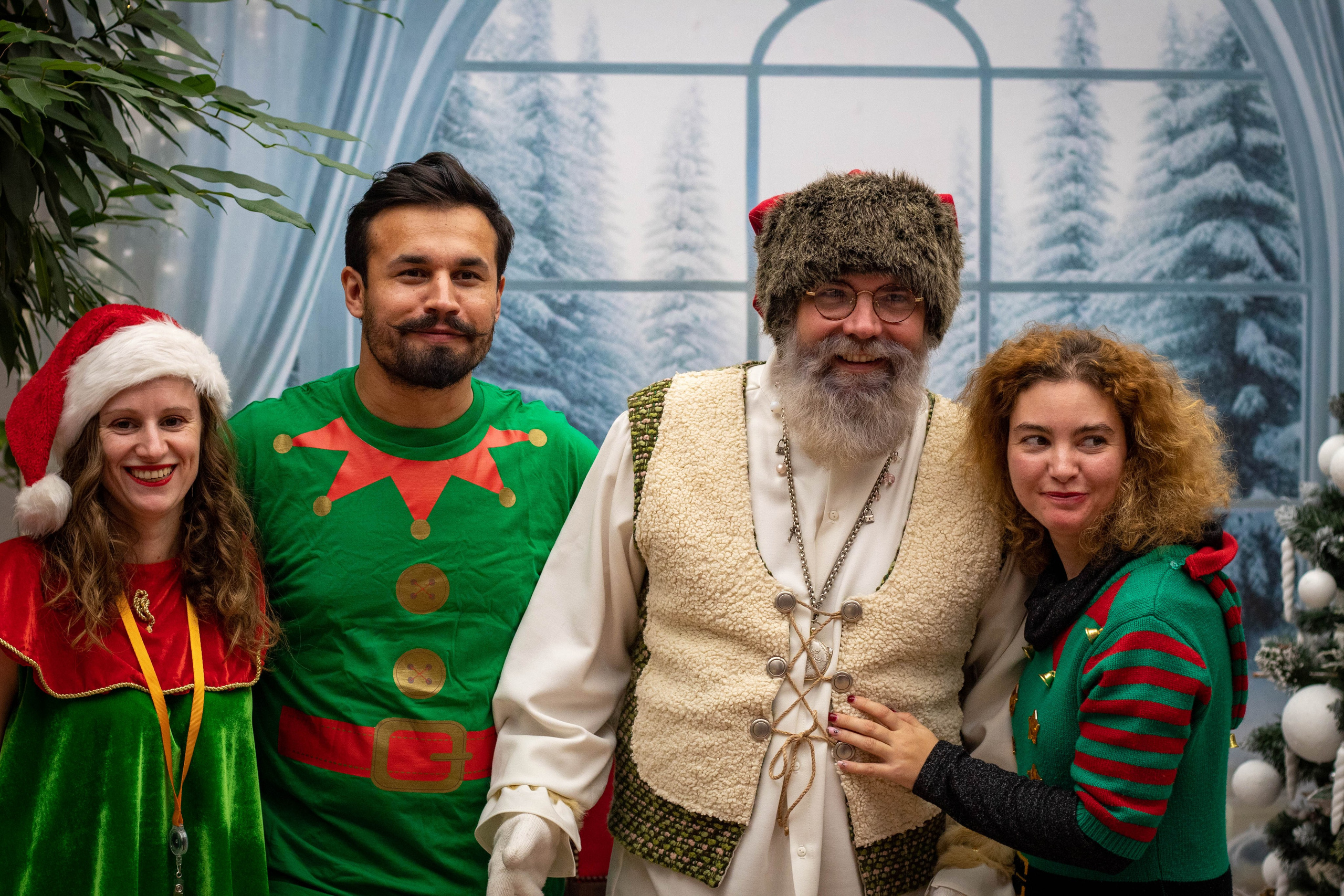 Group of people posing with performers dressed in Christmas-themed costumes, smiling for the camera.