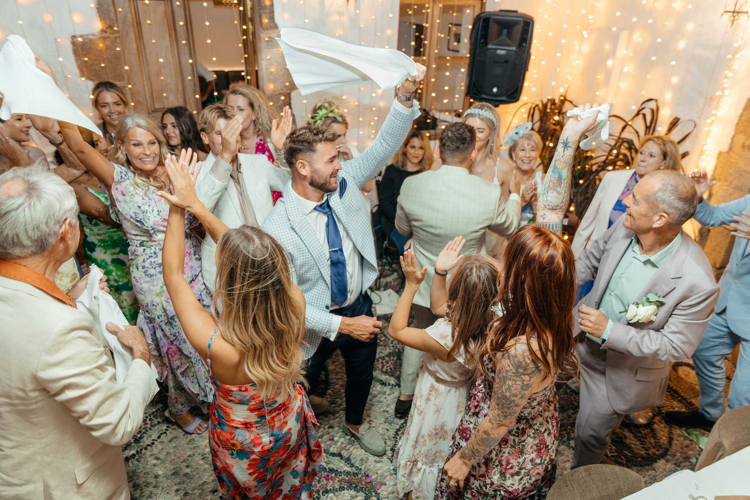 Group of guests dancing and celebrating at the wedding party in a traditional Greek restaurant in Lindos, with the couple joining in the fun.