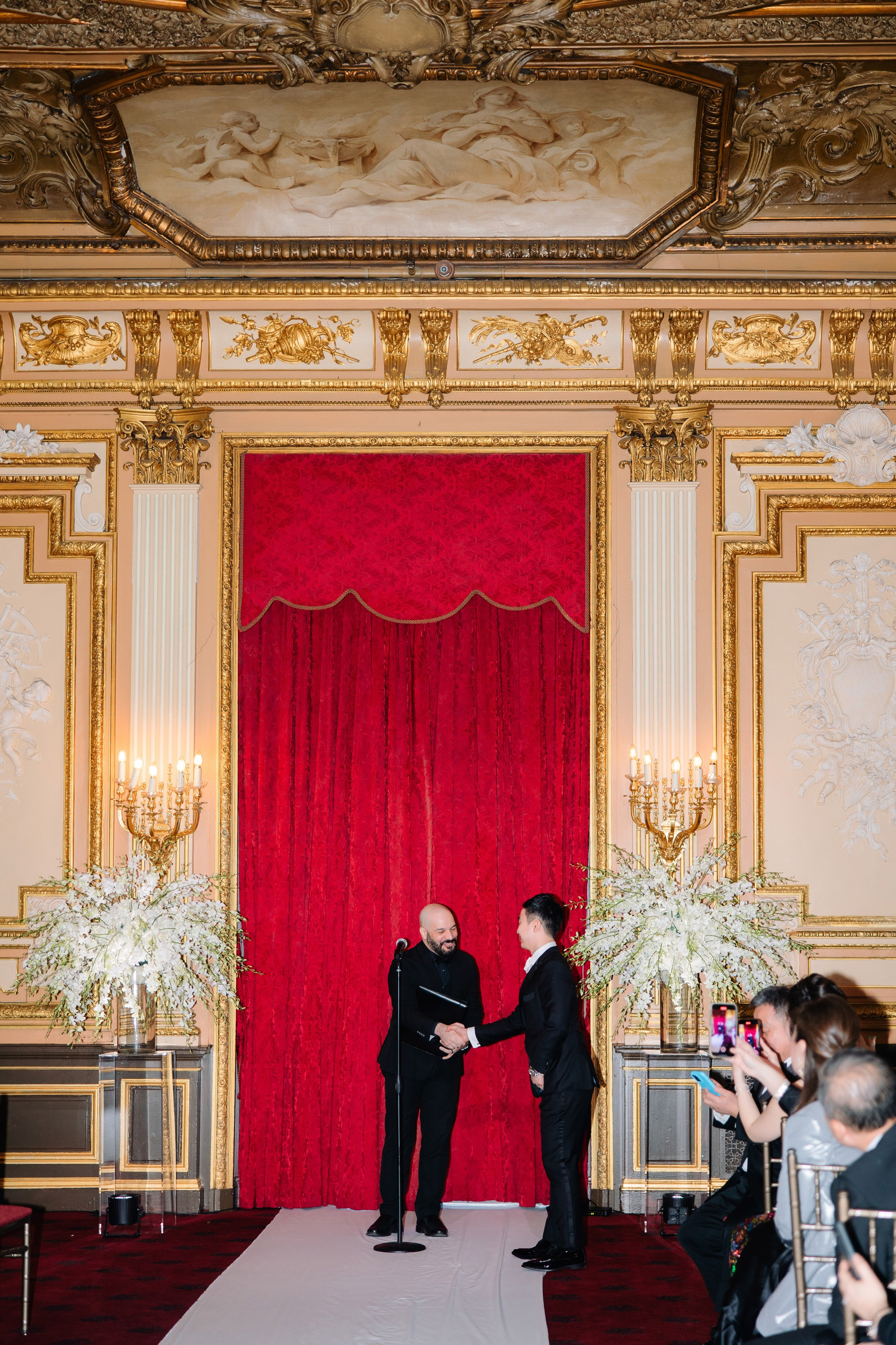 a man and woman standing in front of a red curtain