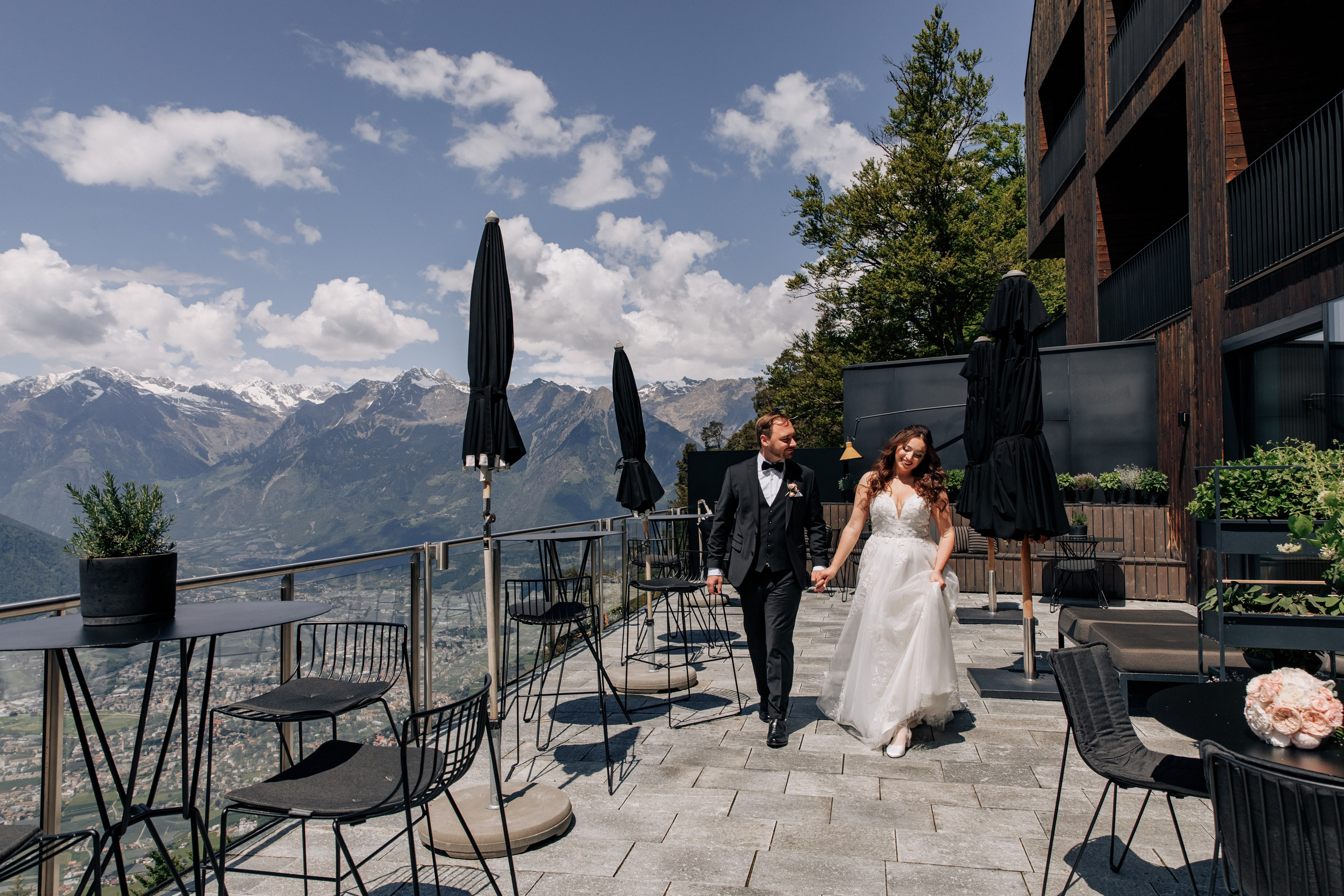 Der Bräutigam und die Braut spazieren Hand in Hand über die Terrasse des Miramonti Boutique Hotels. Ein romantischer Moment im malerischen Ambiente.