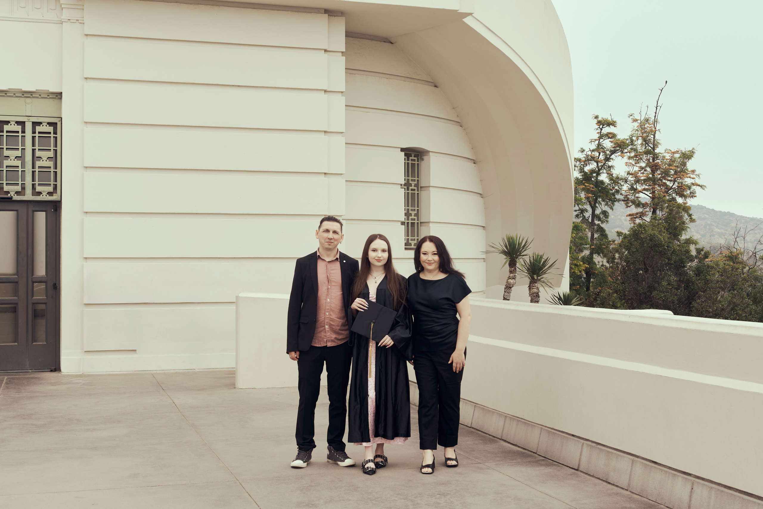 Close-up of a graduate holding their diploma in front of a famous Los Angeles landmark