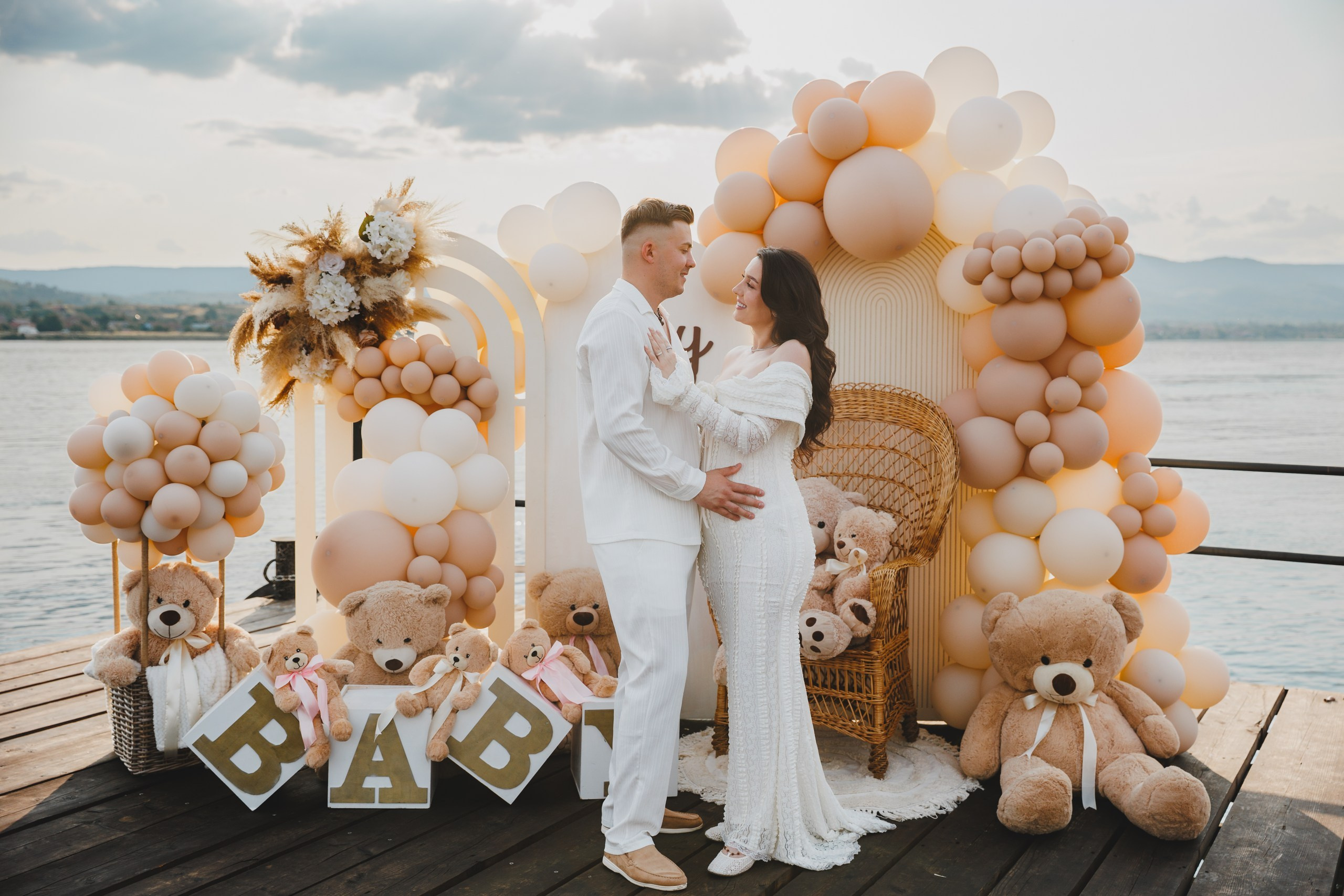 Viitori părinți îmbrățișați lângă decoruri BABY cu baloane
