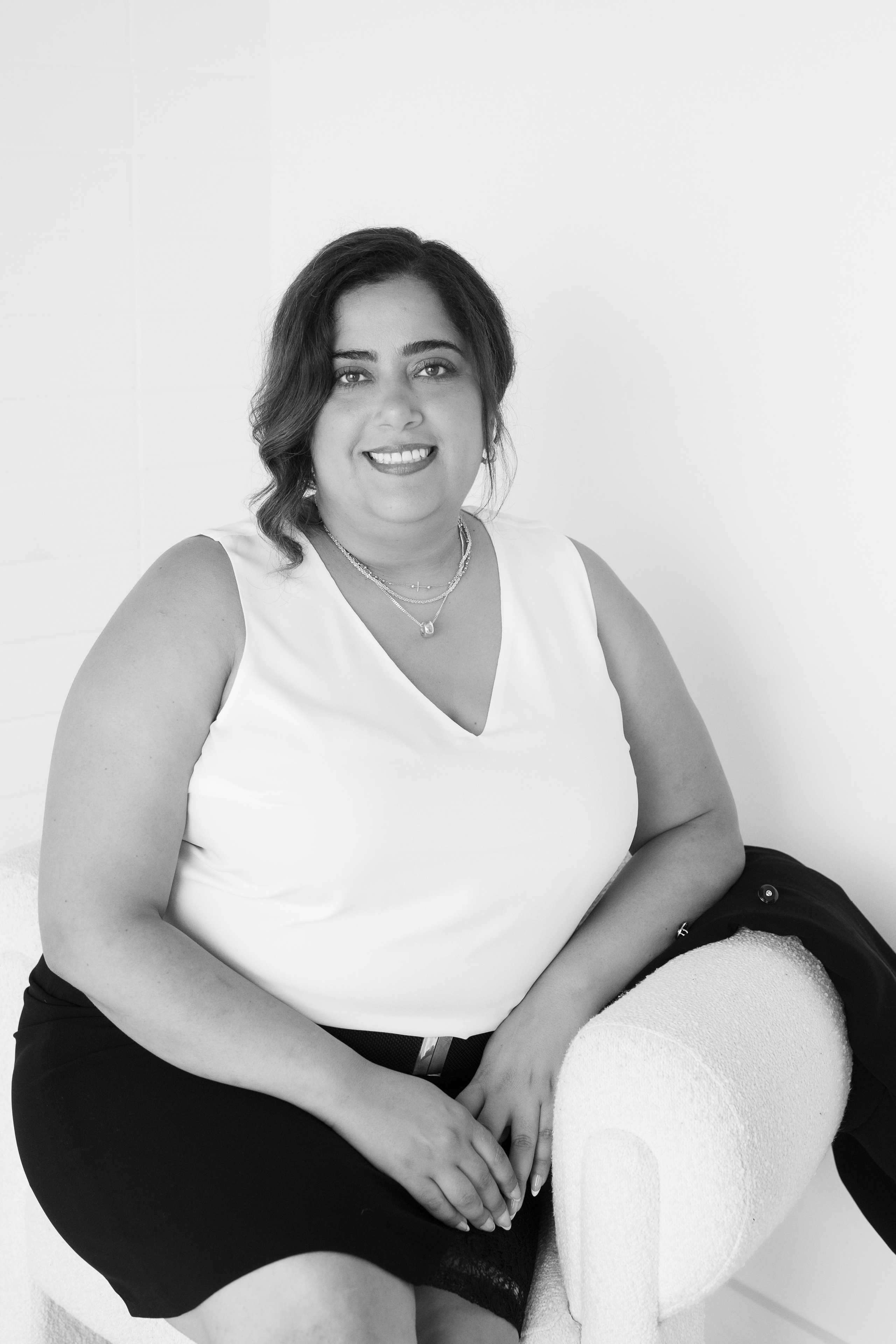 black and white headshot of woman sitting on white chair 