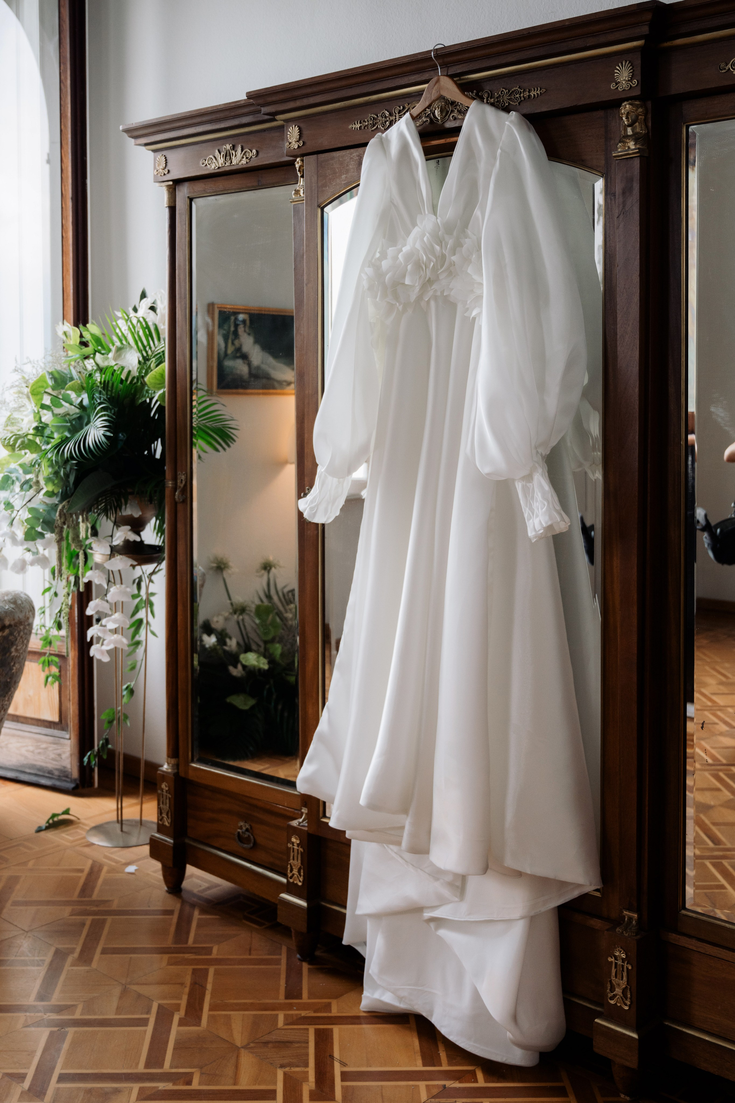 a wedding dress hanging on a wooden hanger