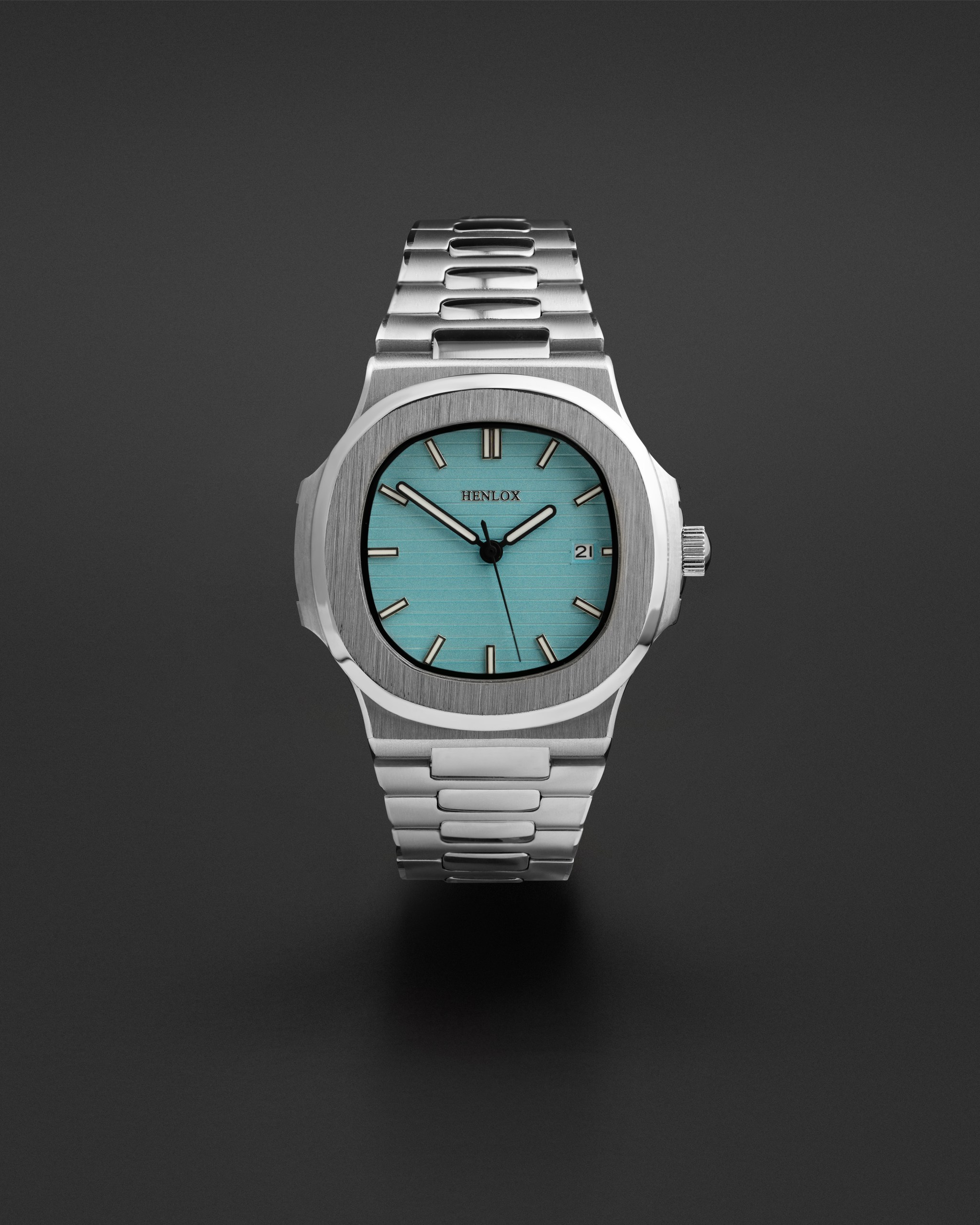 Silver wristwatch with a turquoise dial showcased in a clean product shoot