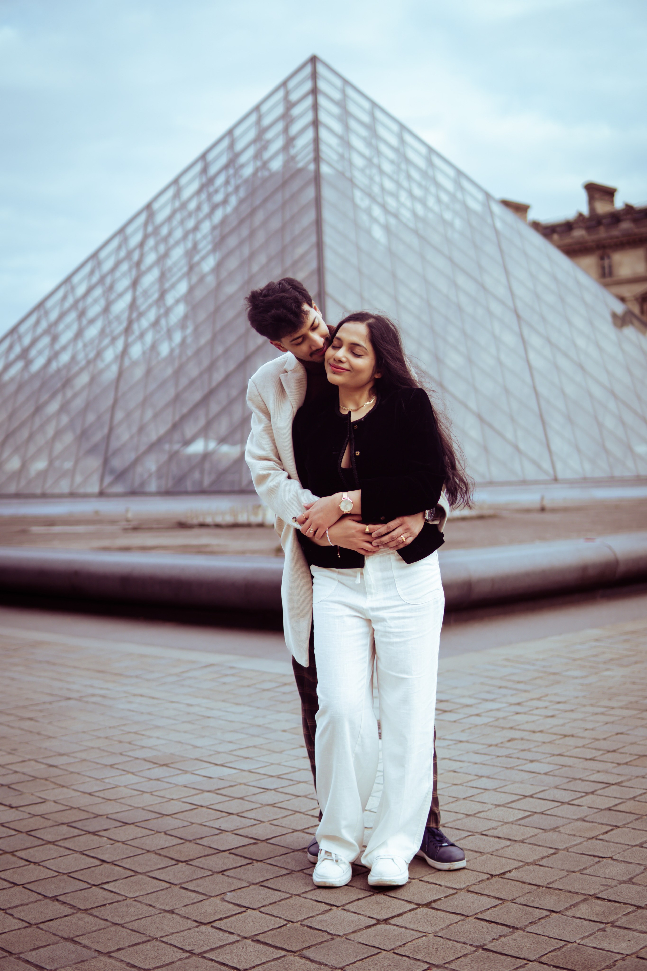 couple standing in front of louvre museum