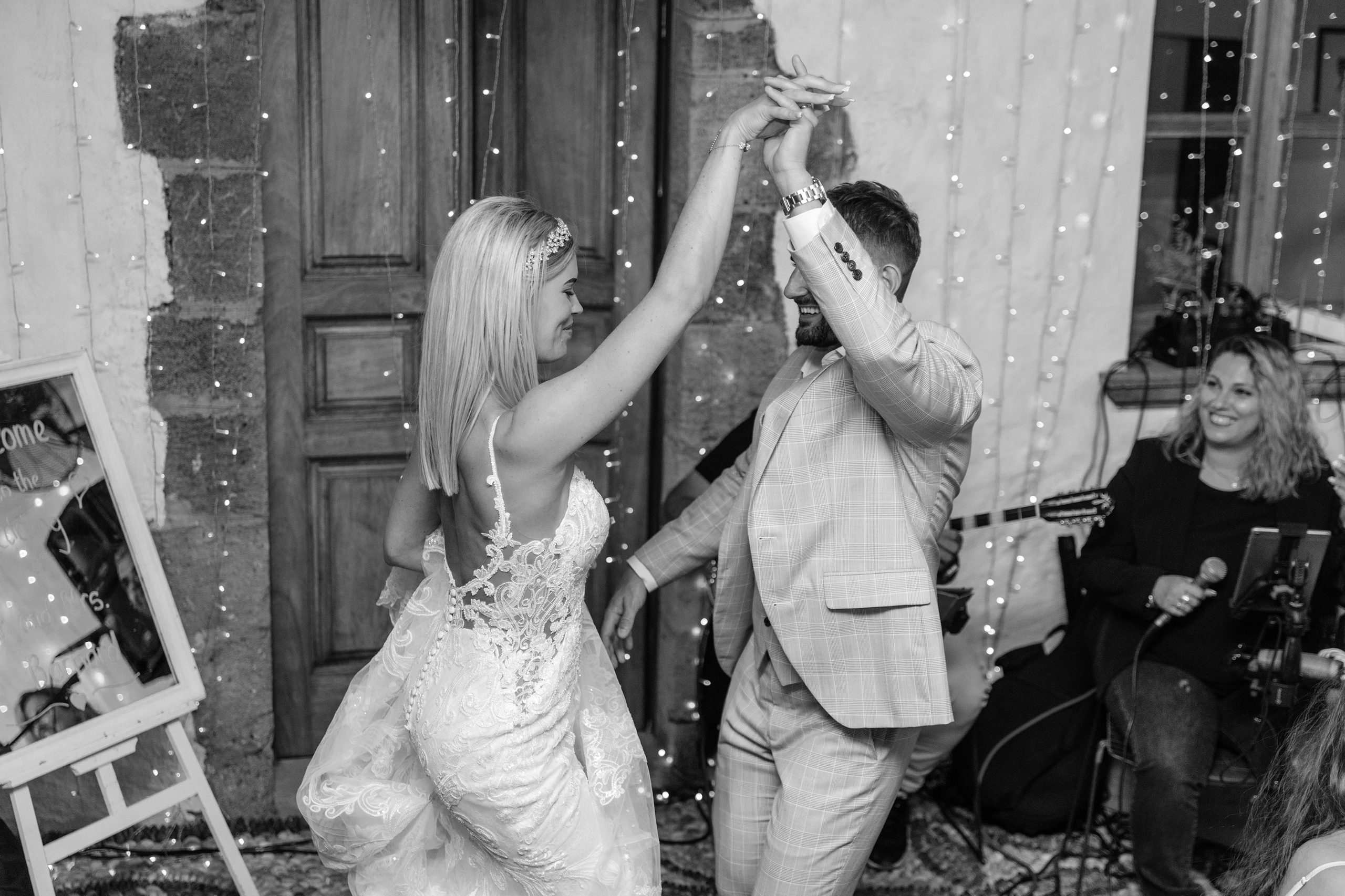 Bride and groom dancing together during their wedding party at a beautifully decorated restaurant in Lindos, Greece, with guests cheering around them.
