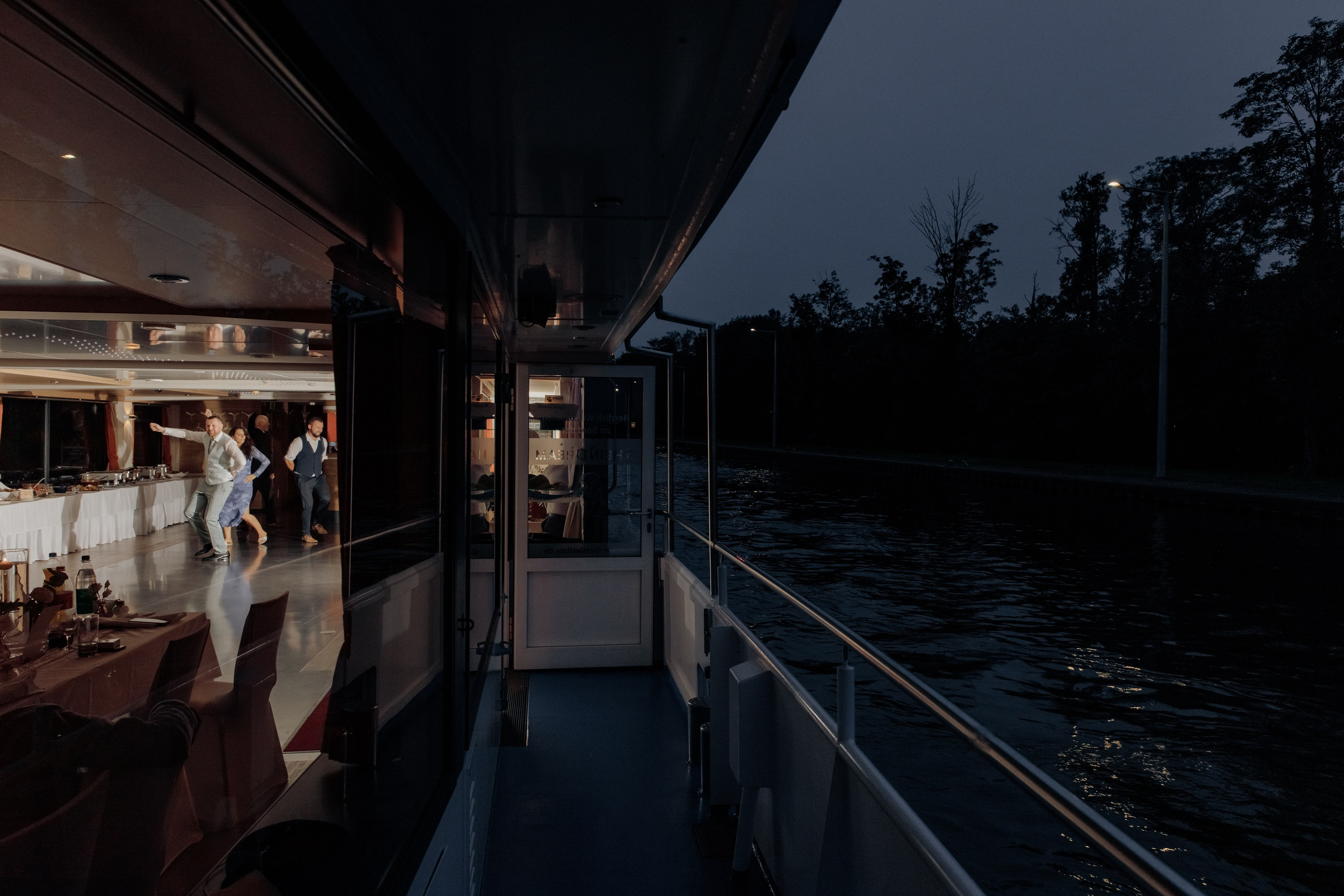 Nachts findet auf dem festlich beleuchteten Schiff eine Hochzeitsparty statt. Ein lebendiger und stimmungsvoller Moment der Feier.
