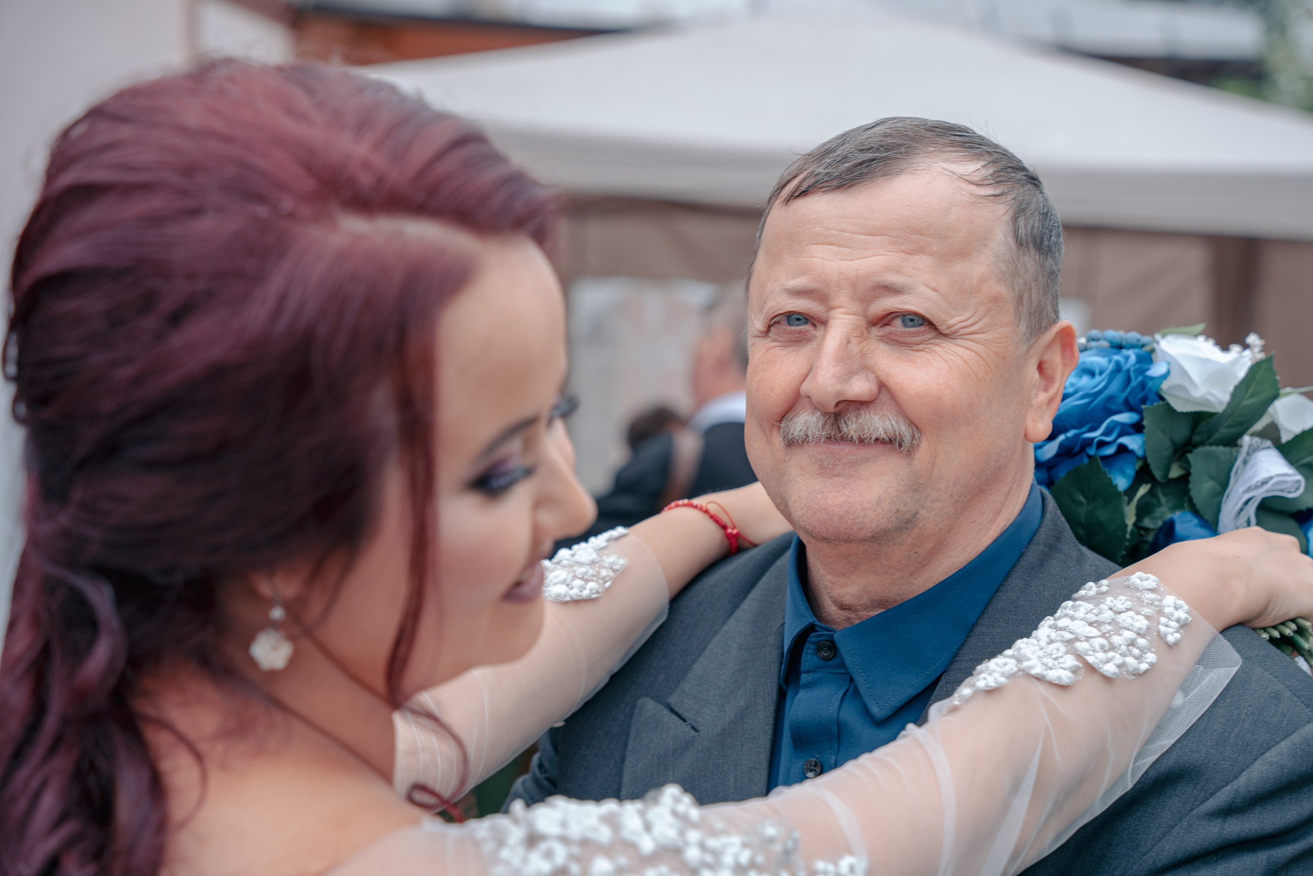 Portret la nuntă în București, mireasă îmbrățișând un invitat drag, detalii dantelă rochie și buchet cu trandafiri albaștri, incadru.ro.