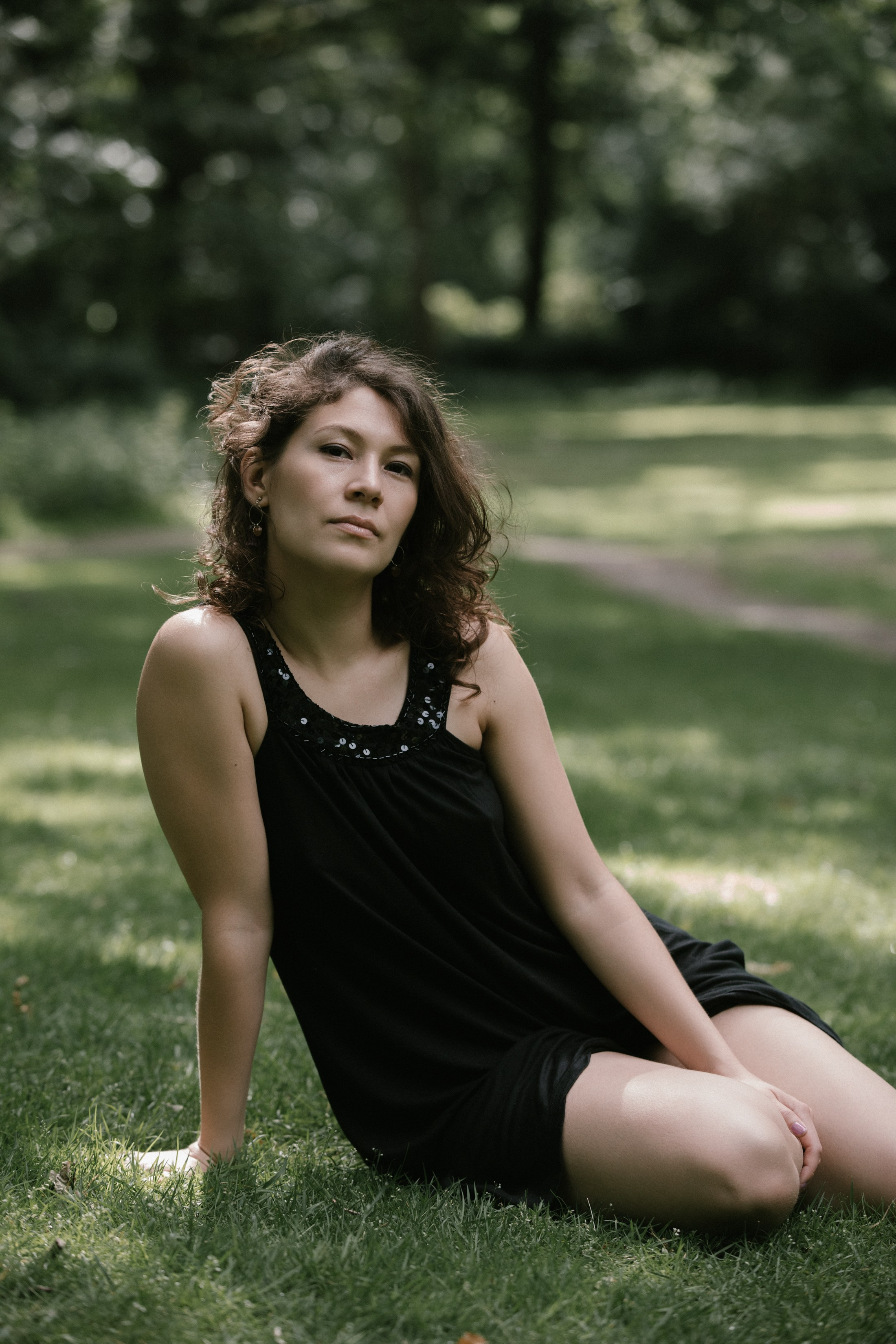 Tänzerin sitzt im Tiergarten Berlin im Sonnenlicht