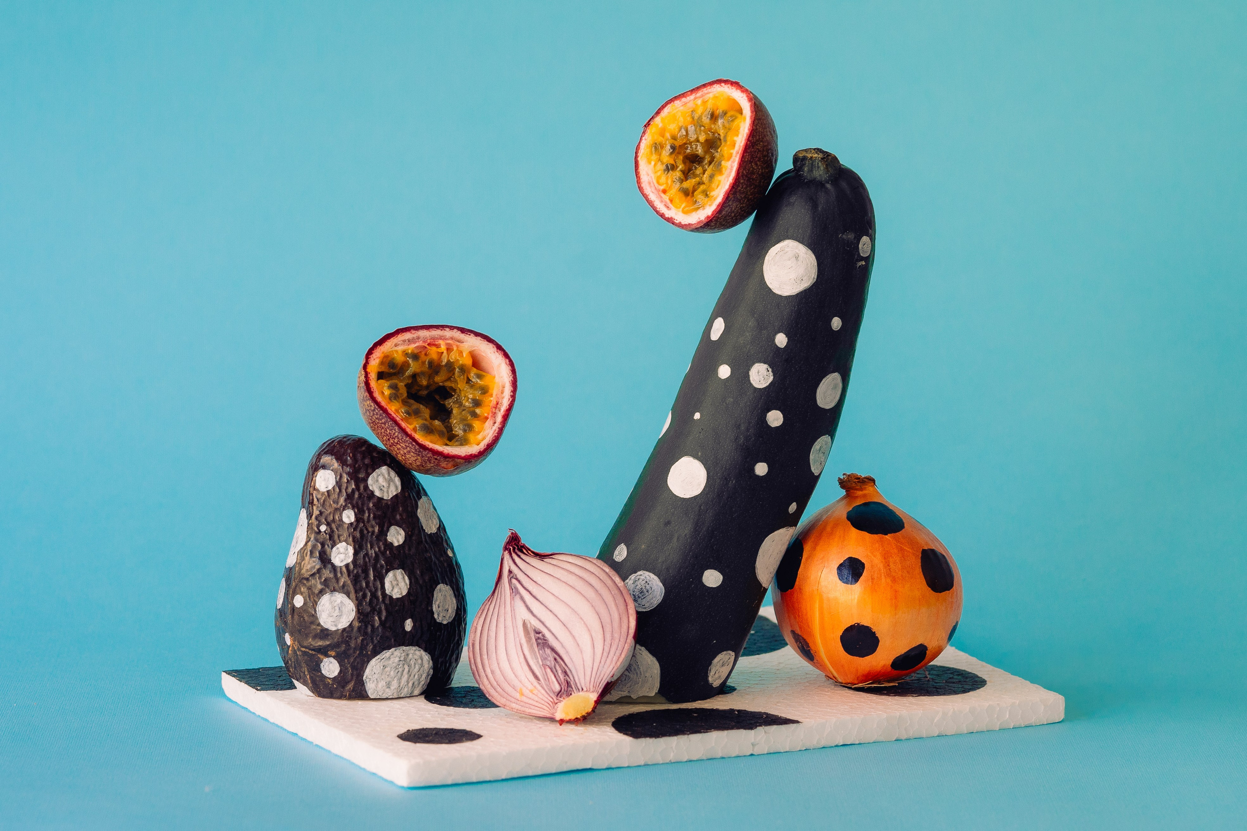 Spotted Pattern Painted Vegetable Art Composition. Artistic arrangement of spotted pattern-painted vegetables on a vivid blue background.