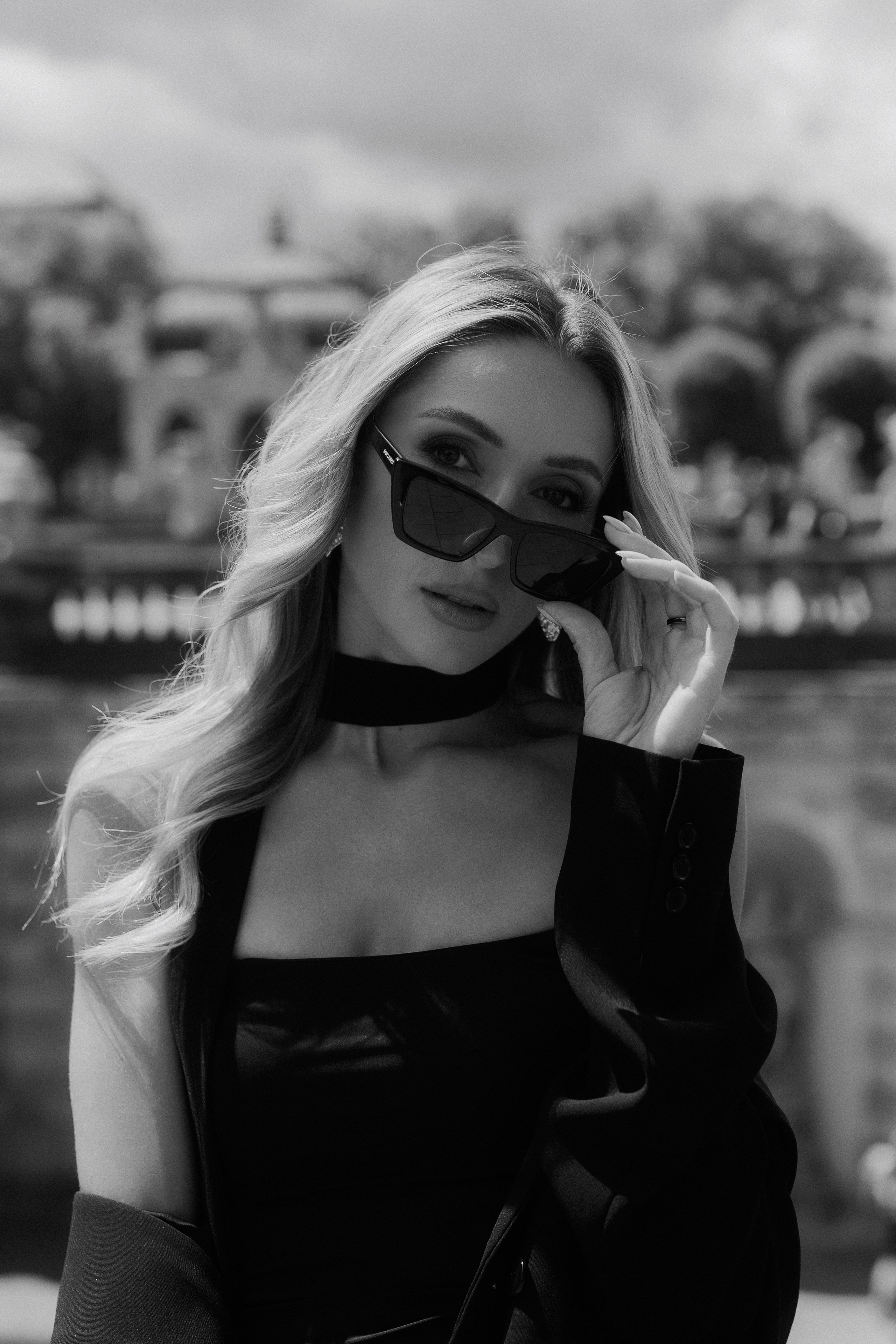 Close-up black and white portrait of an elegant woman wearing sunglasses and looking into the camera in Dresden, Germany. Editorial female portrait photography available in Dresden, Leipzig and Wurzen. Крупный чёрно-белый портрет элегантной девушки в солнцезащитных очках, смотрящей в камеру, в Дрездене, Германия. Редакционная женская портретная фотография в Дрездене, Лейпциге и Вурцене.