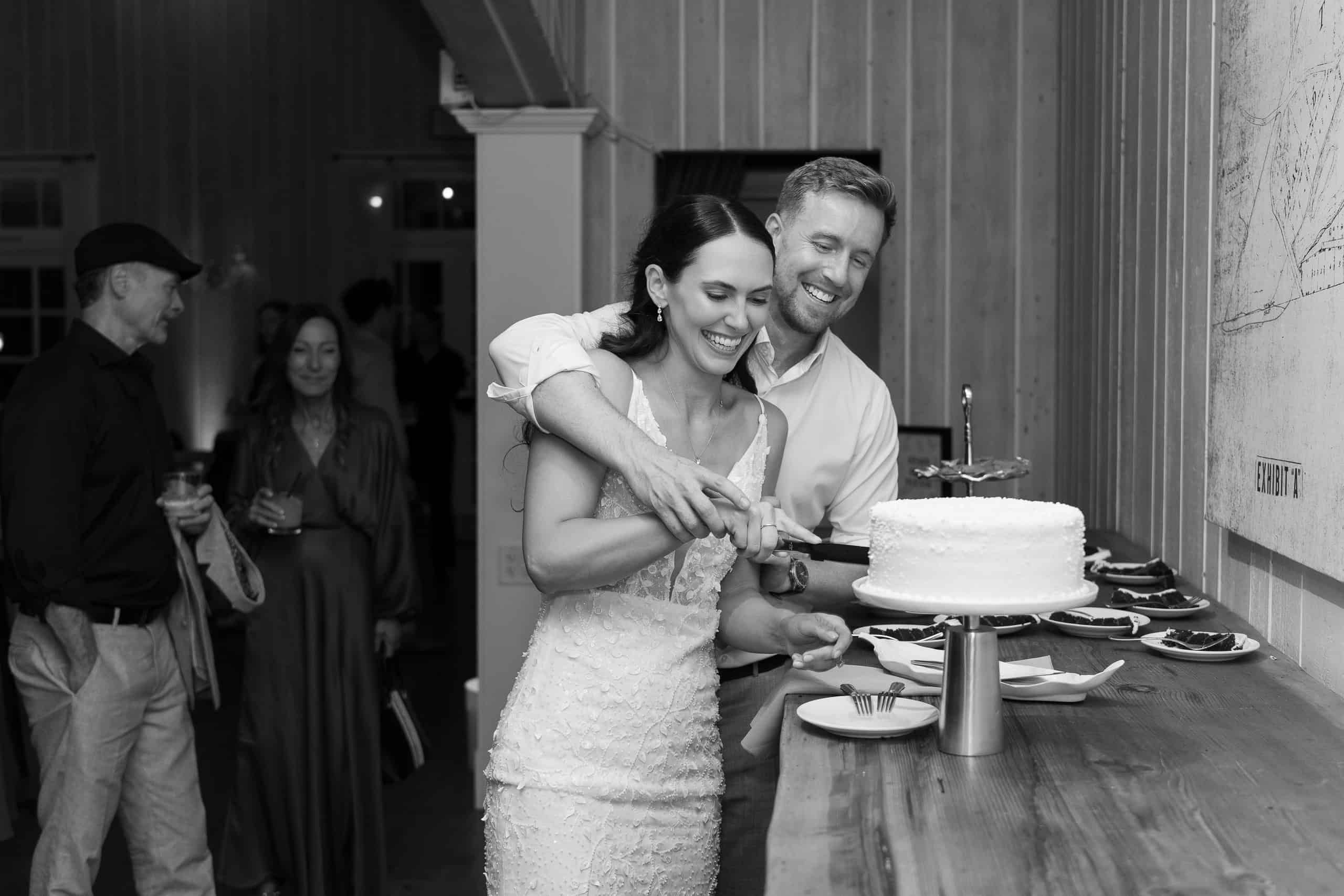 Bride and groom laughing while cutting the cake