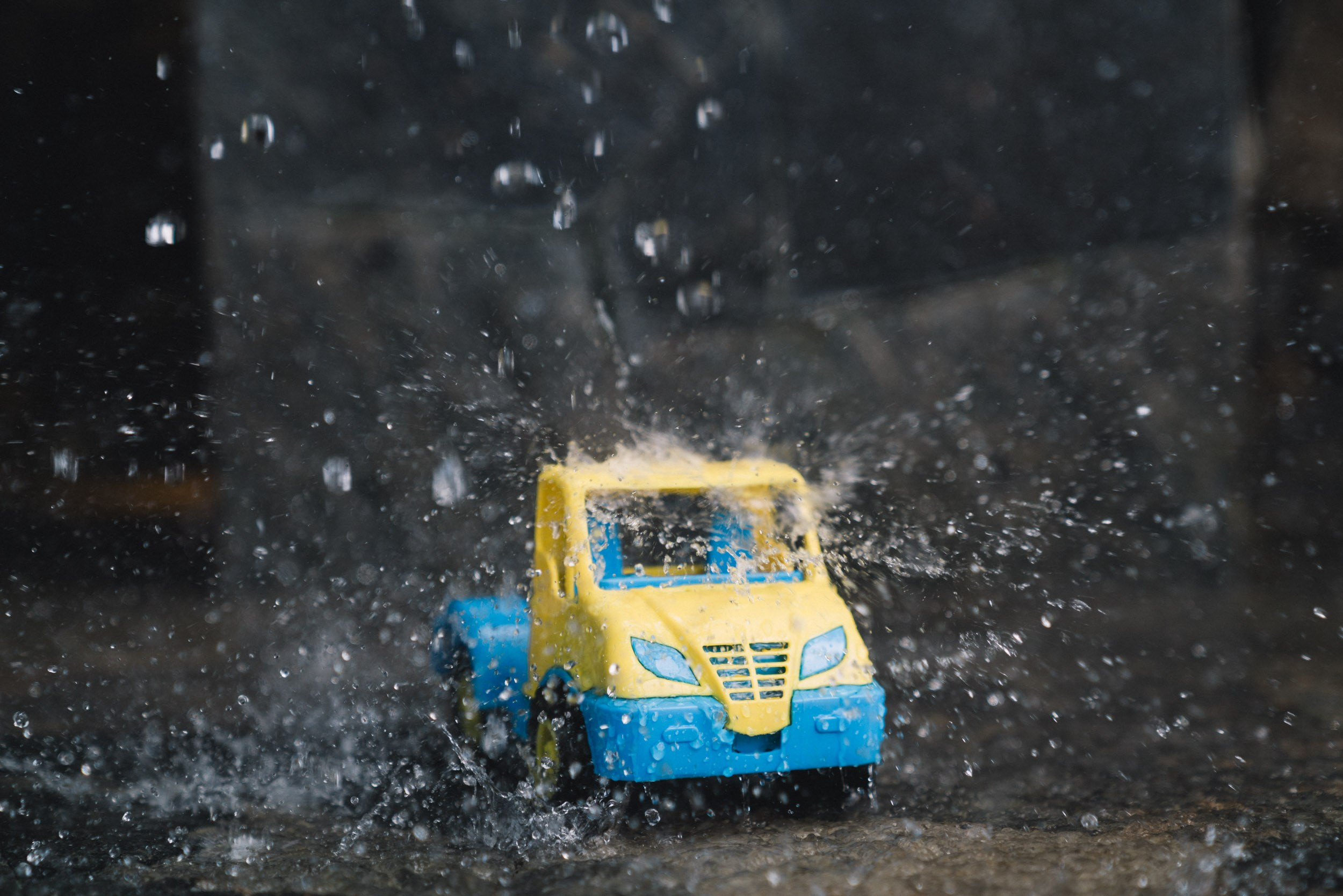 Toy blue and yellow car showered with water