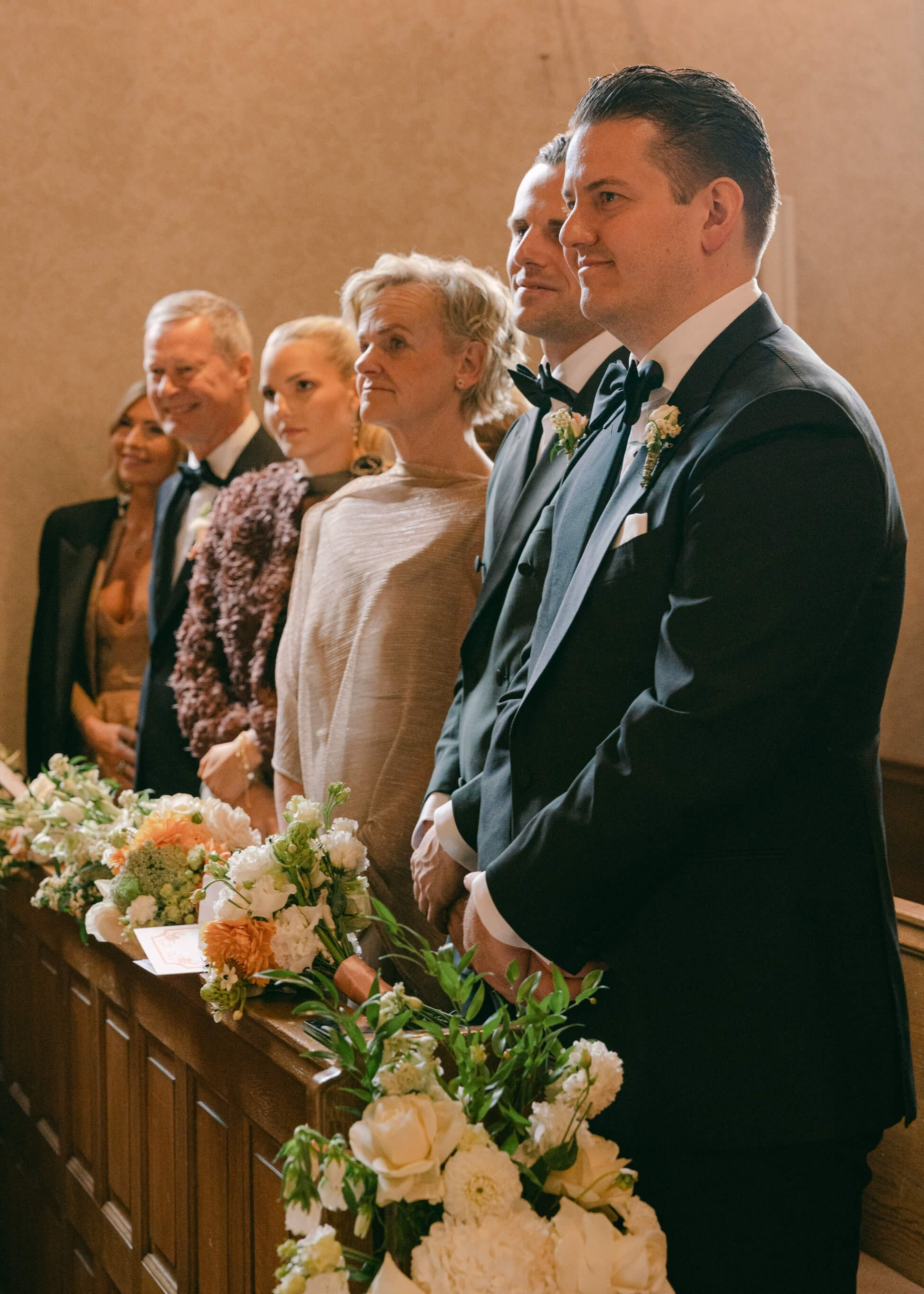Groom with wedding guest smiling near white floral arrangement at church ceremony, luxury wedding Frankfurt
