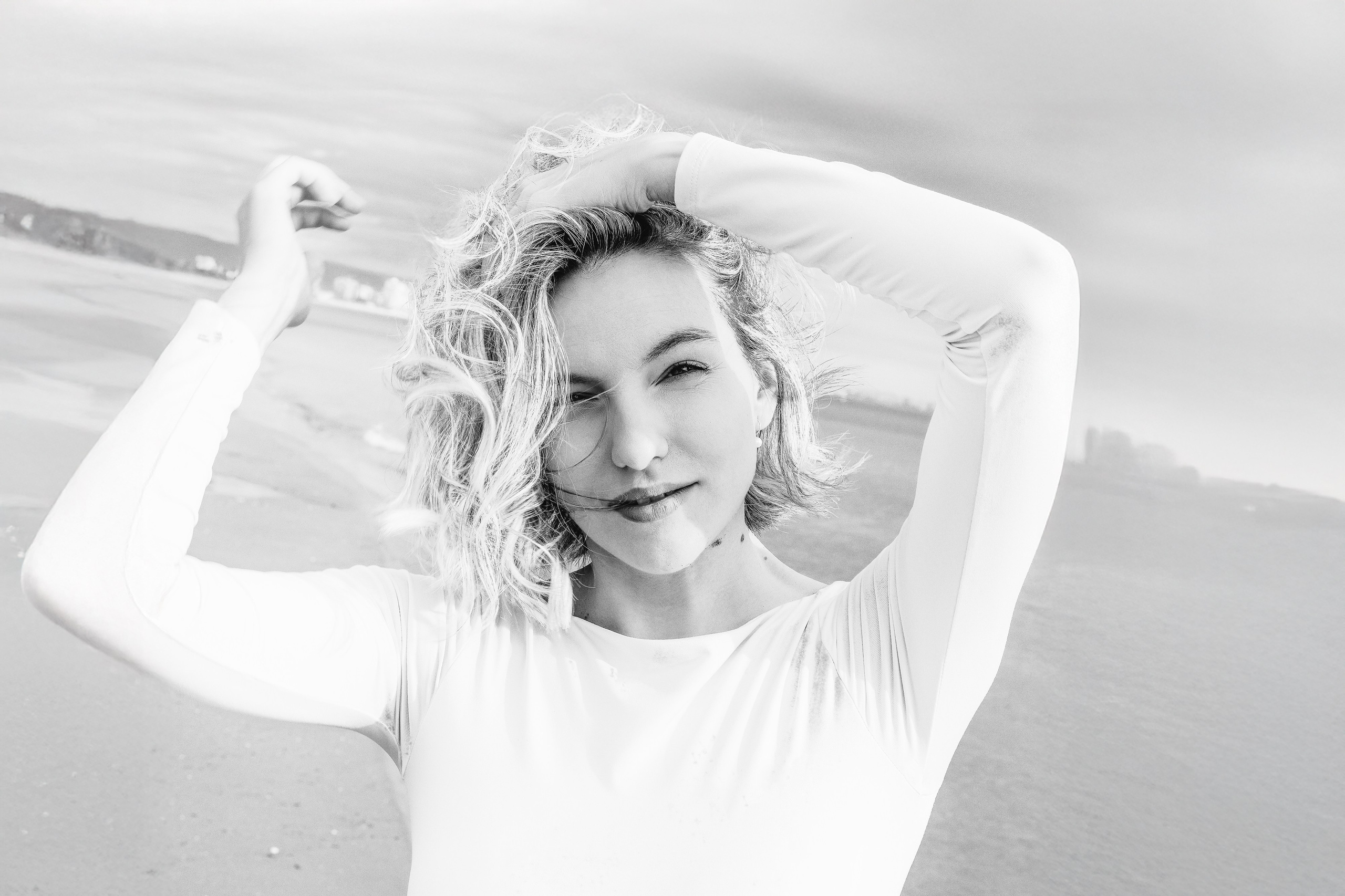 Художественный черно-белый женский портрет на пляже, снятый в Валенсии, Испания, с изображением уверенной женщины с развевающимися светлыми волосами и естественным выражением лица — отличный выбор для тех, кто ищет элегантную и креативную женскую портретную фотосъёмку в Валенсии и Испании.