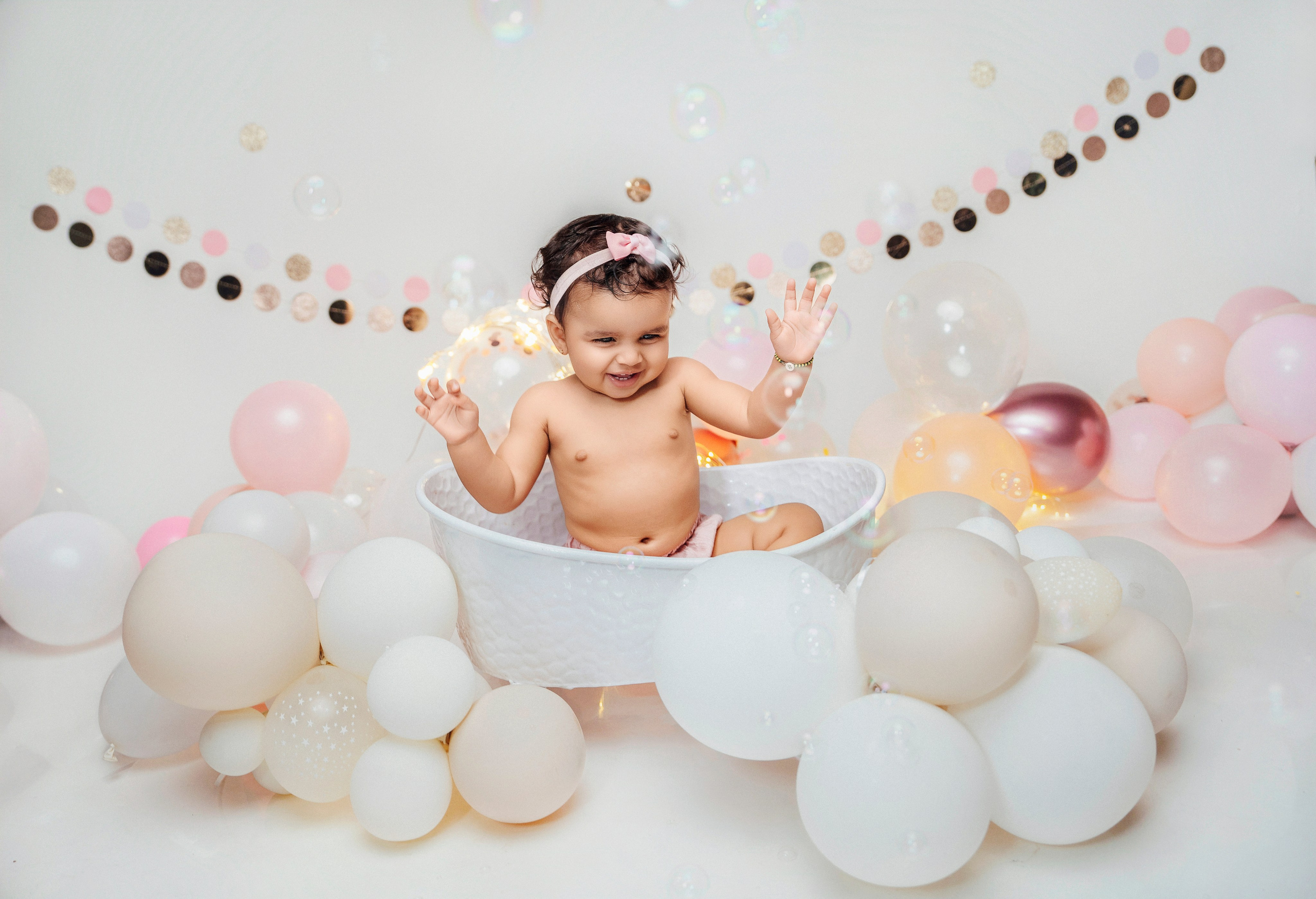 Малышка в ванночке, окружённая пастельными шарами, во время съёмки Cake Smash на Тенерифе