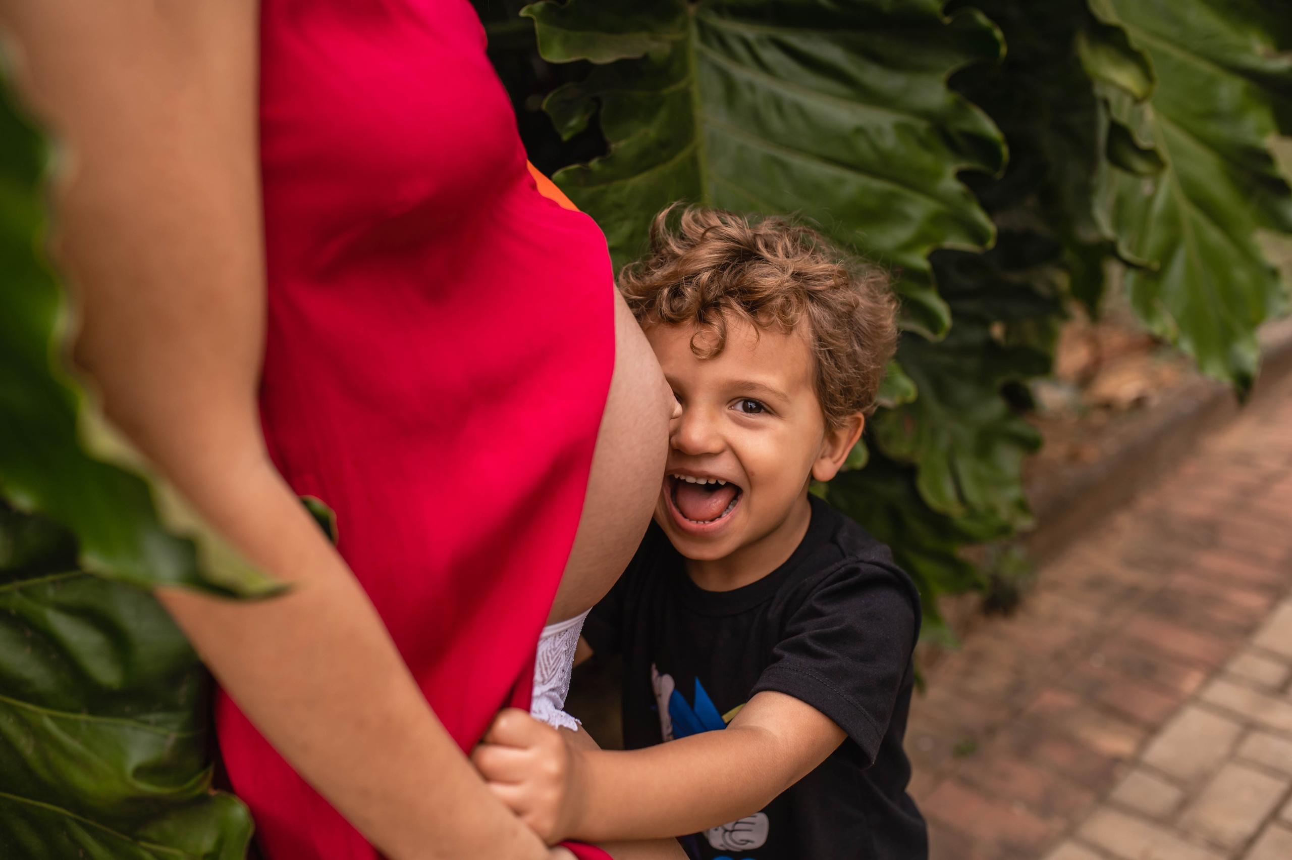 Ensaio gestante com filho em Juiz de Fora, menino abraçando a barriga da mãe com expressão genuína
