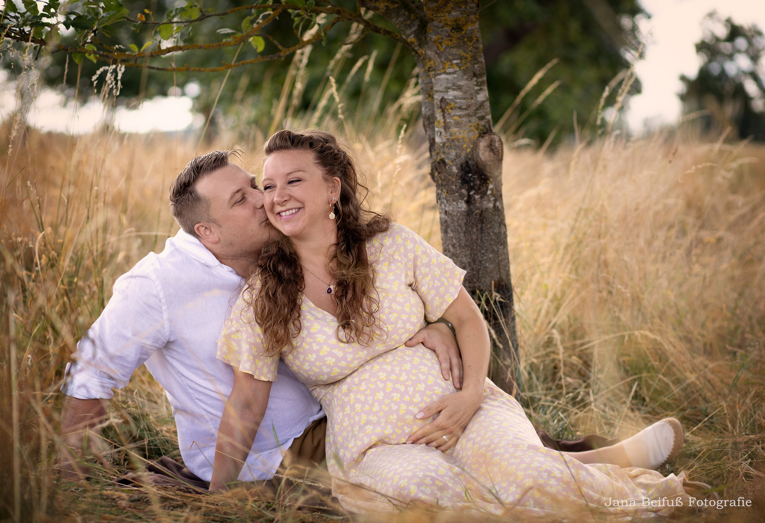 werdende Eltern lachen und küssen sich im Weizenfeld in Weißenhorn - Schwangerschaftsfotograf Jana Beifuß in Weißenhorn bei Ulm 