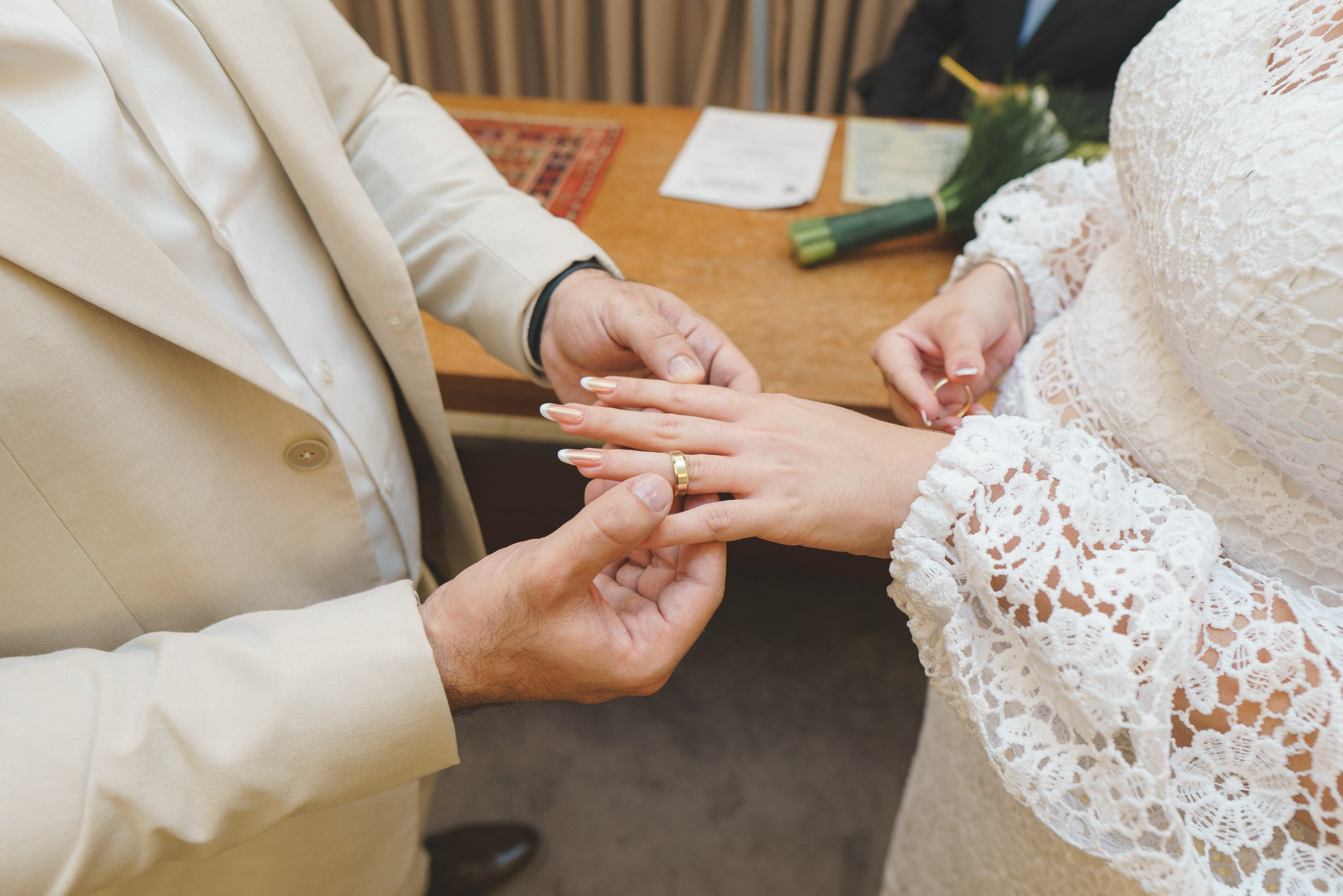 noivo colocando a aliança de casamento na mão da noiva muito emocionado