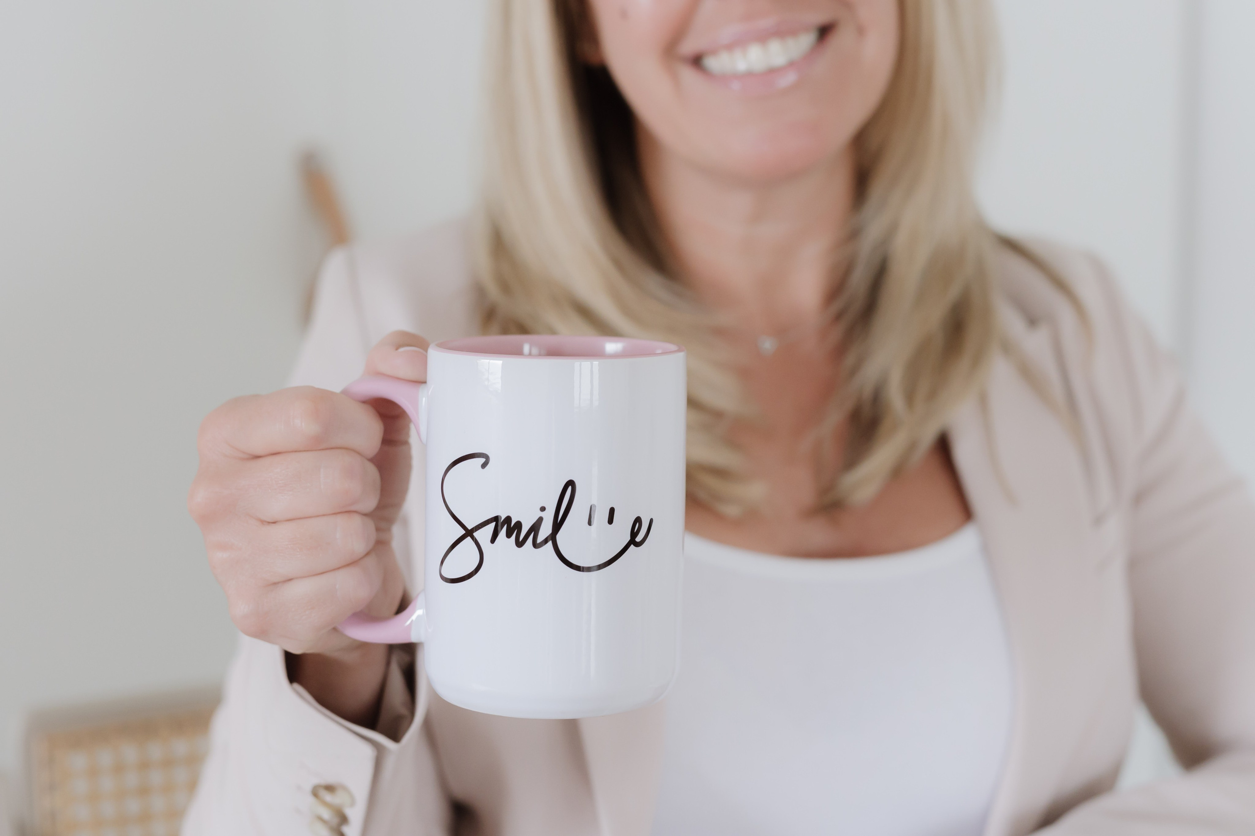 Close up photo of a woman's hand holding a mug that says SMILE