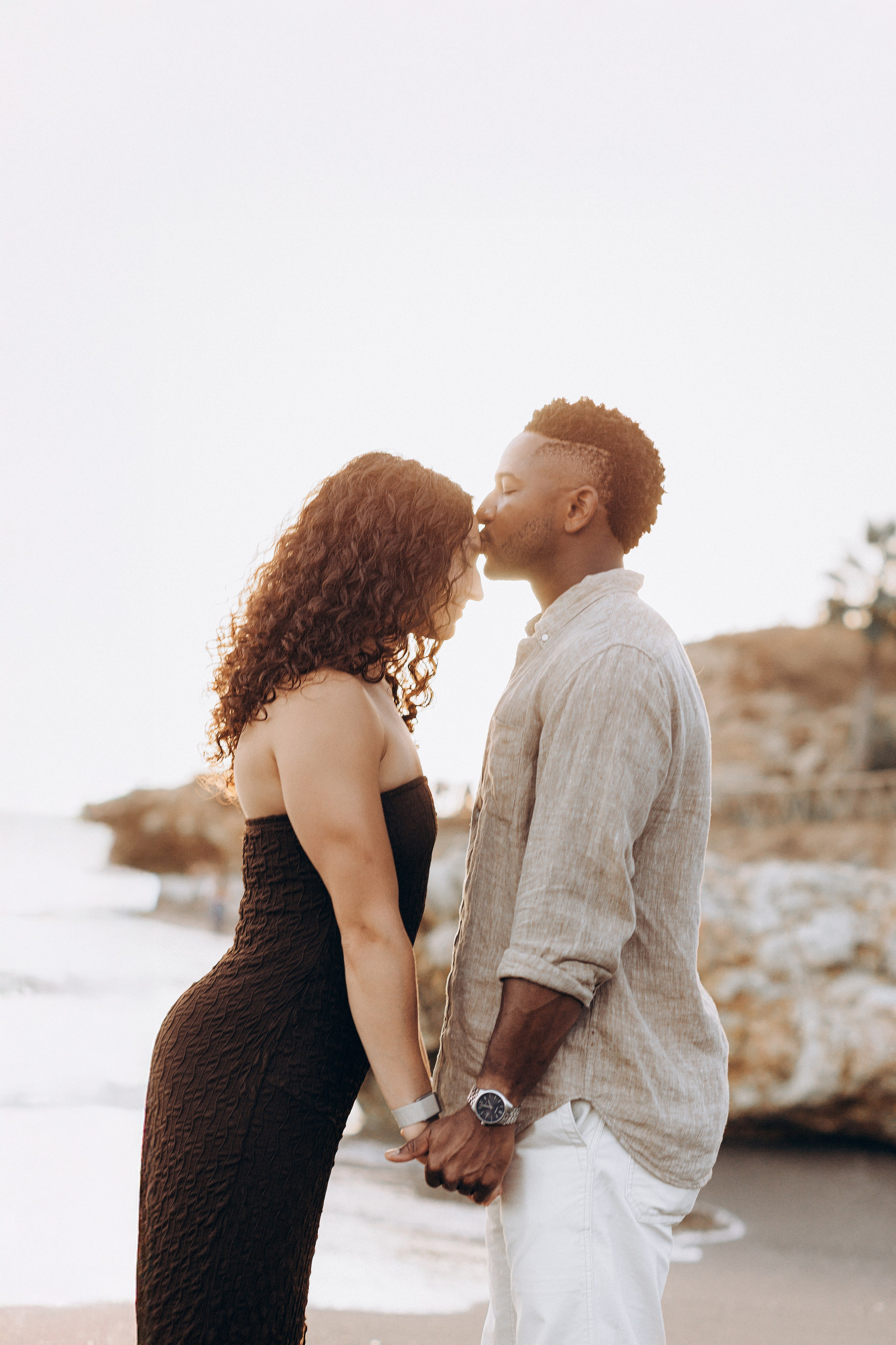 Romantic destination engagement photoshoot in Málaga with the couple holding hands by the Mediterranean coastline. Intimate post-proposal moment captured during a sunset engagement session in southern Spain.