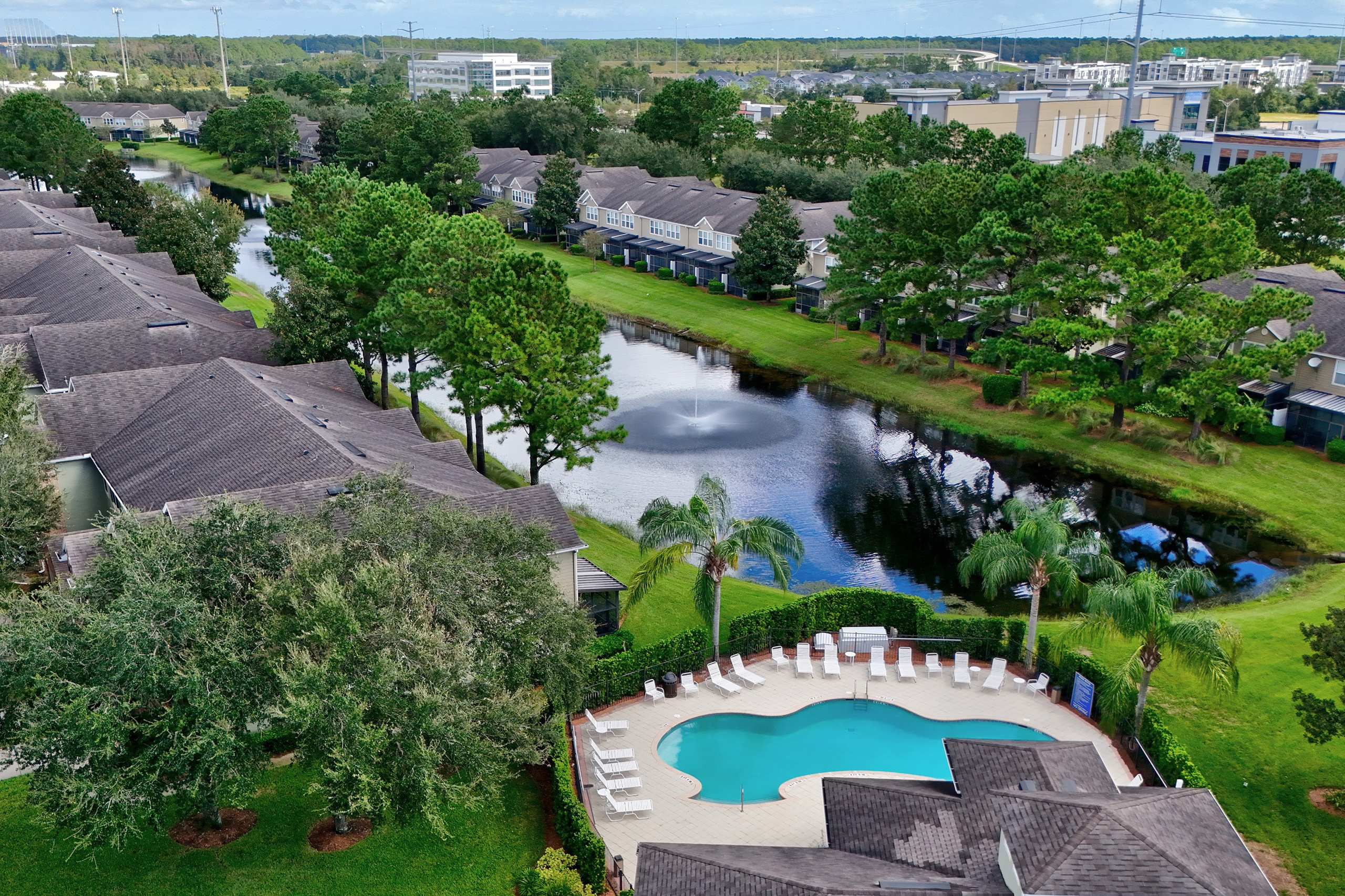 Scenic drone shot of neighborhood pool surrounded by trees and water