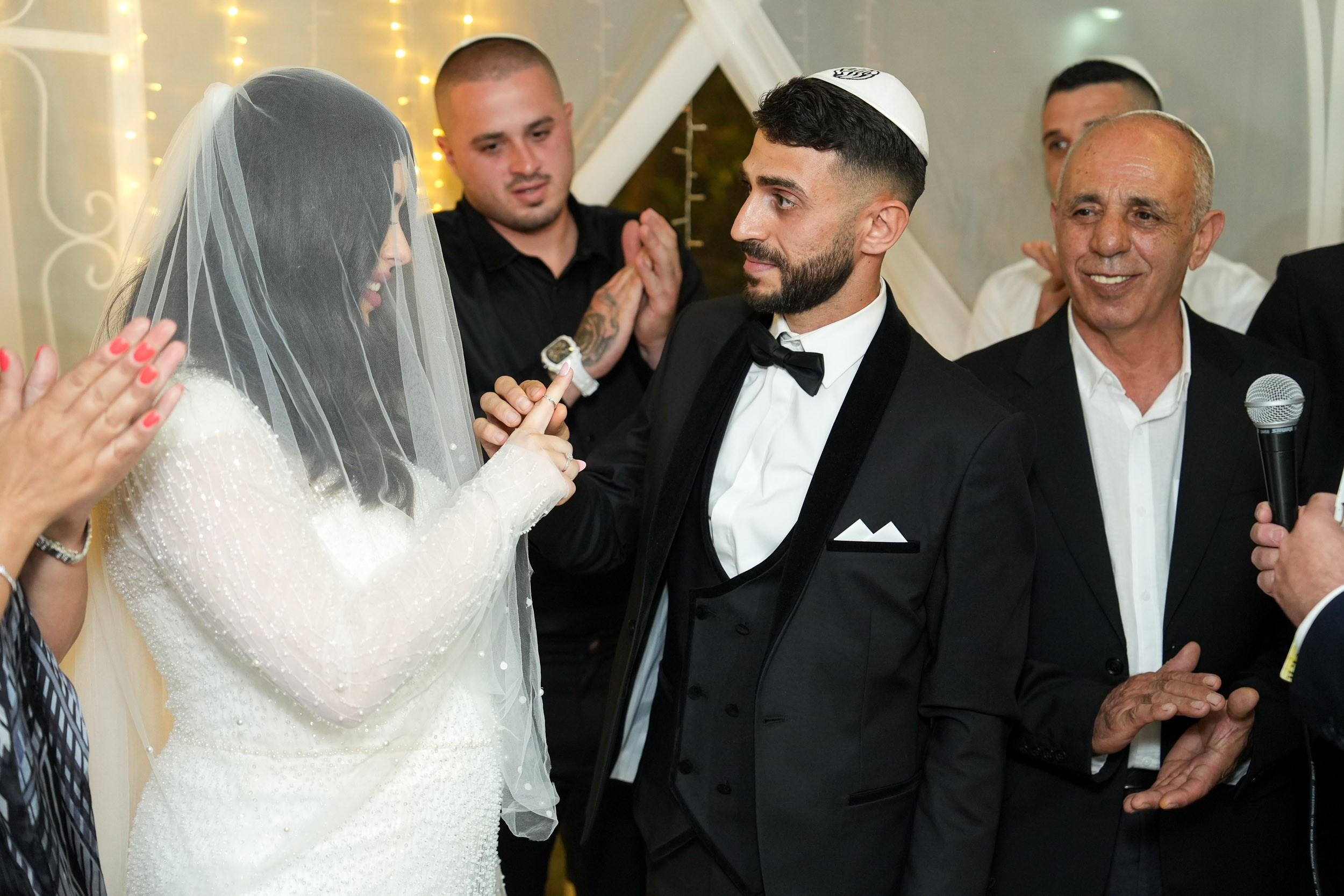 Groom Shimon placing a ring on bride Natali's finger during the Chuppah ceremony at 88 Event Garden in Emek Hefer, Israel
