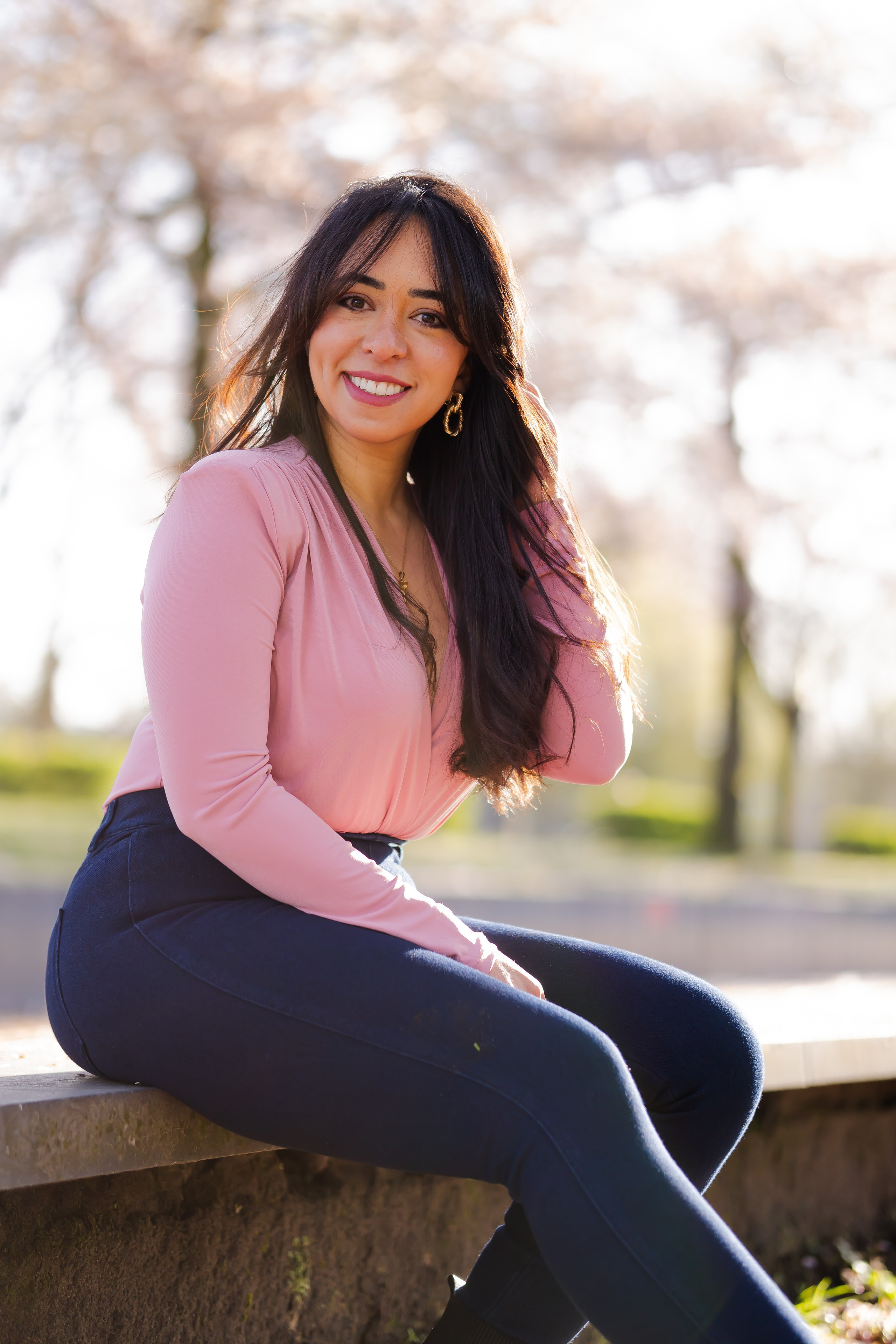 girl sitting on an edge in a cherry blossoms garden