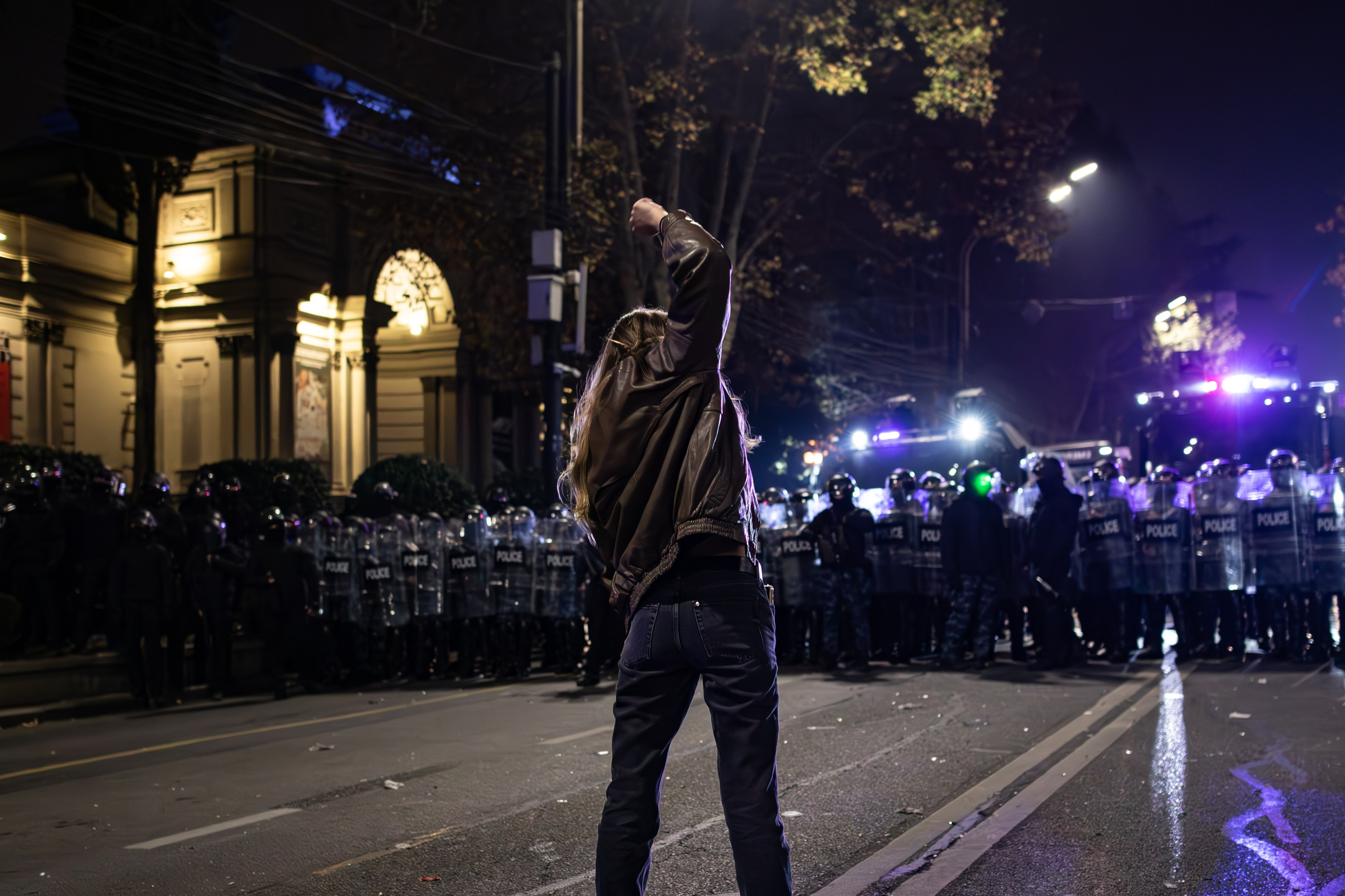 Une jeune femme géorgienne, le poing levé, fait face aux forces de l’ordre.