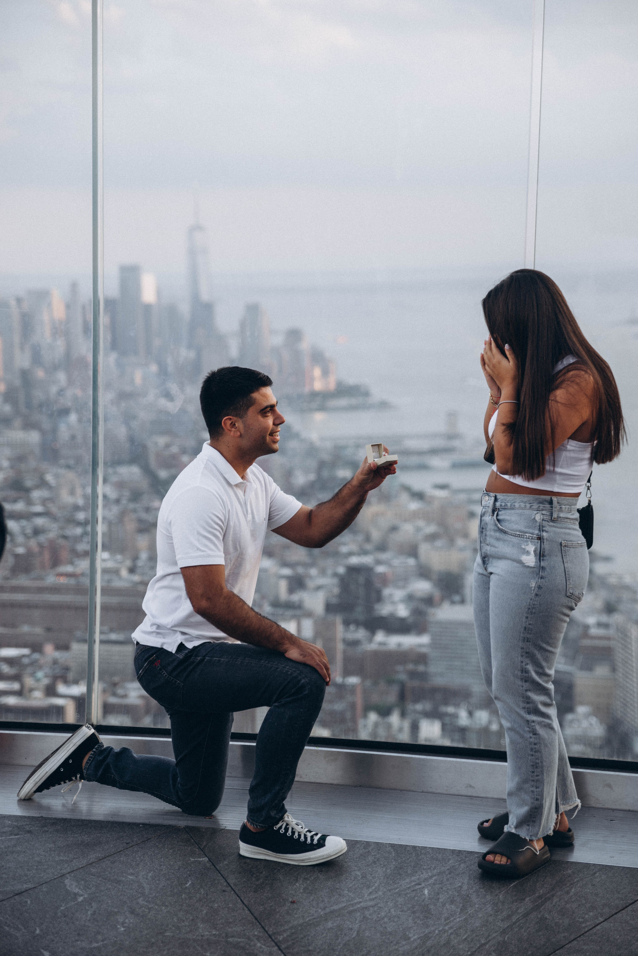 Couple celebrating proposal on Brooklyn Bridge walkway.