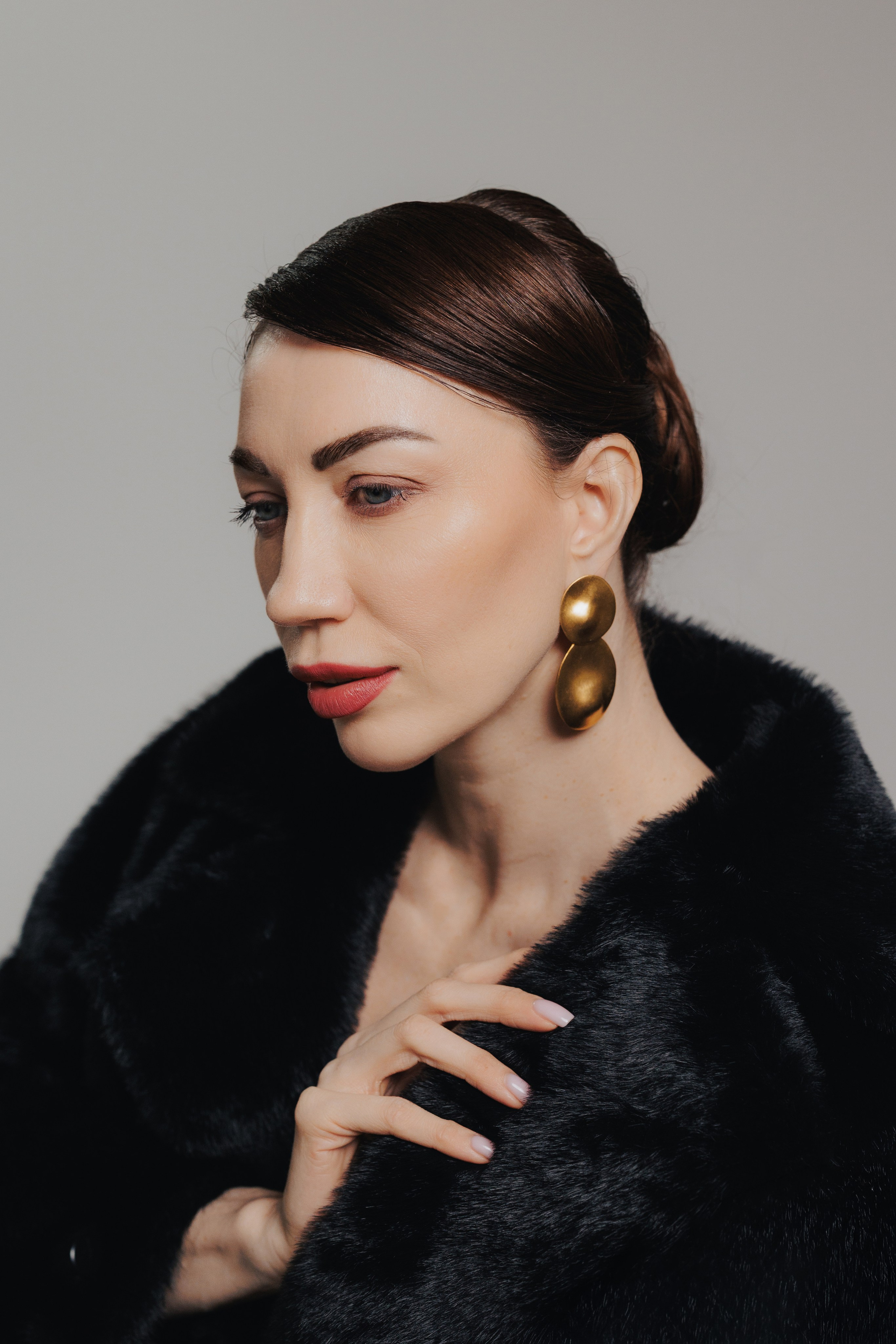 Close-up editorial portrait of an elegant woman with statement earrings and dramatic studio lighting. Крупный редакционный портрет элегантной женщины с выразительными серьгами и драматичным студийным светом.
